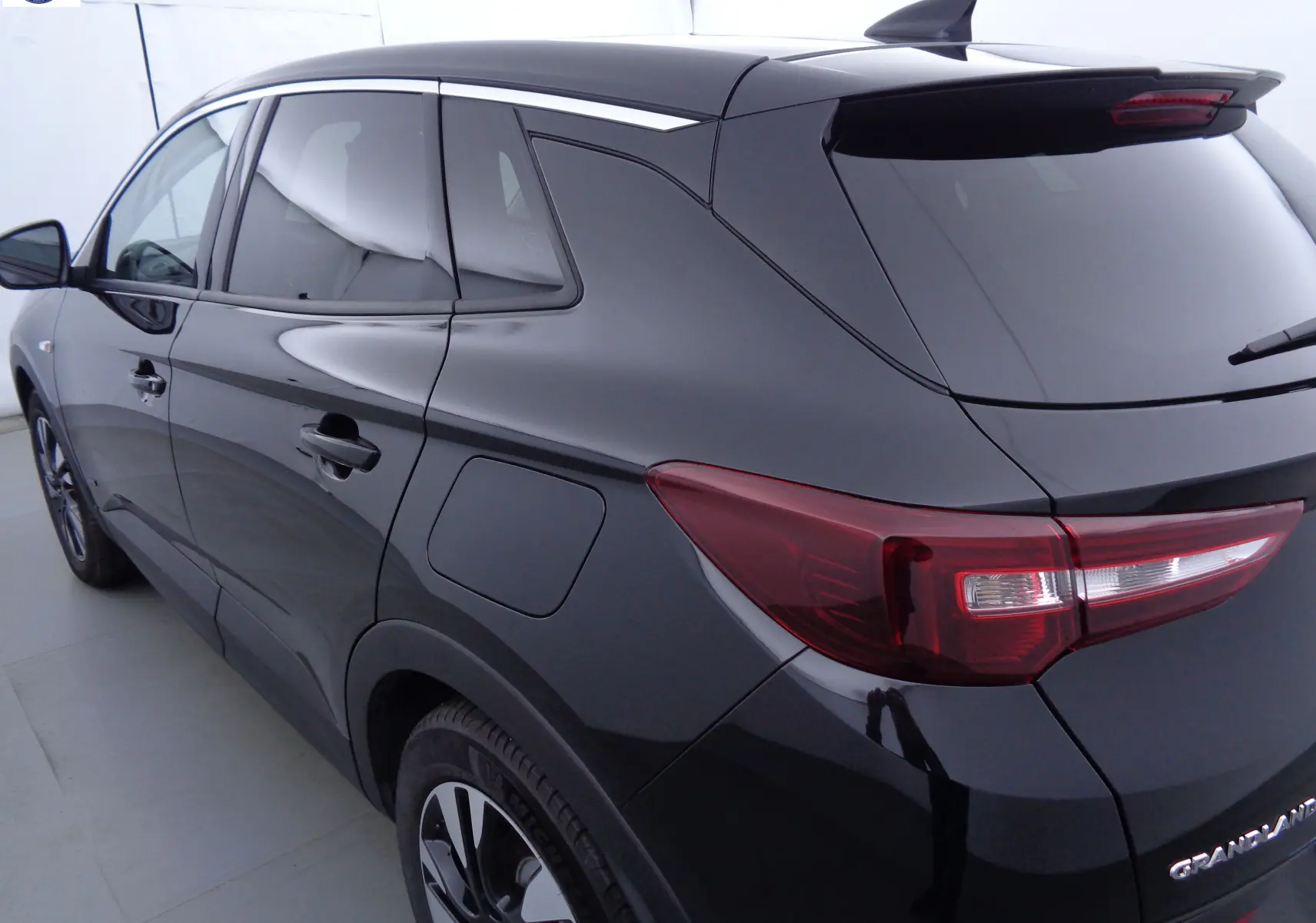 Vue 3/4 arrière droite d'un Opel Grandland X noir métal, avec feux arrière LED et toit noir brillant.