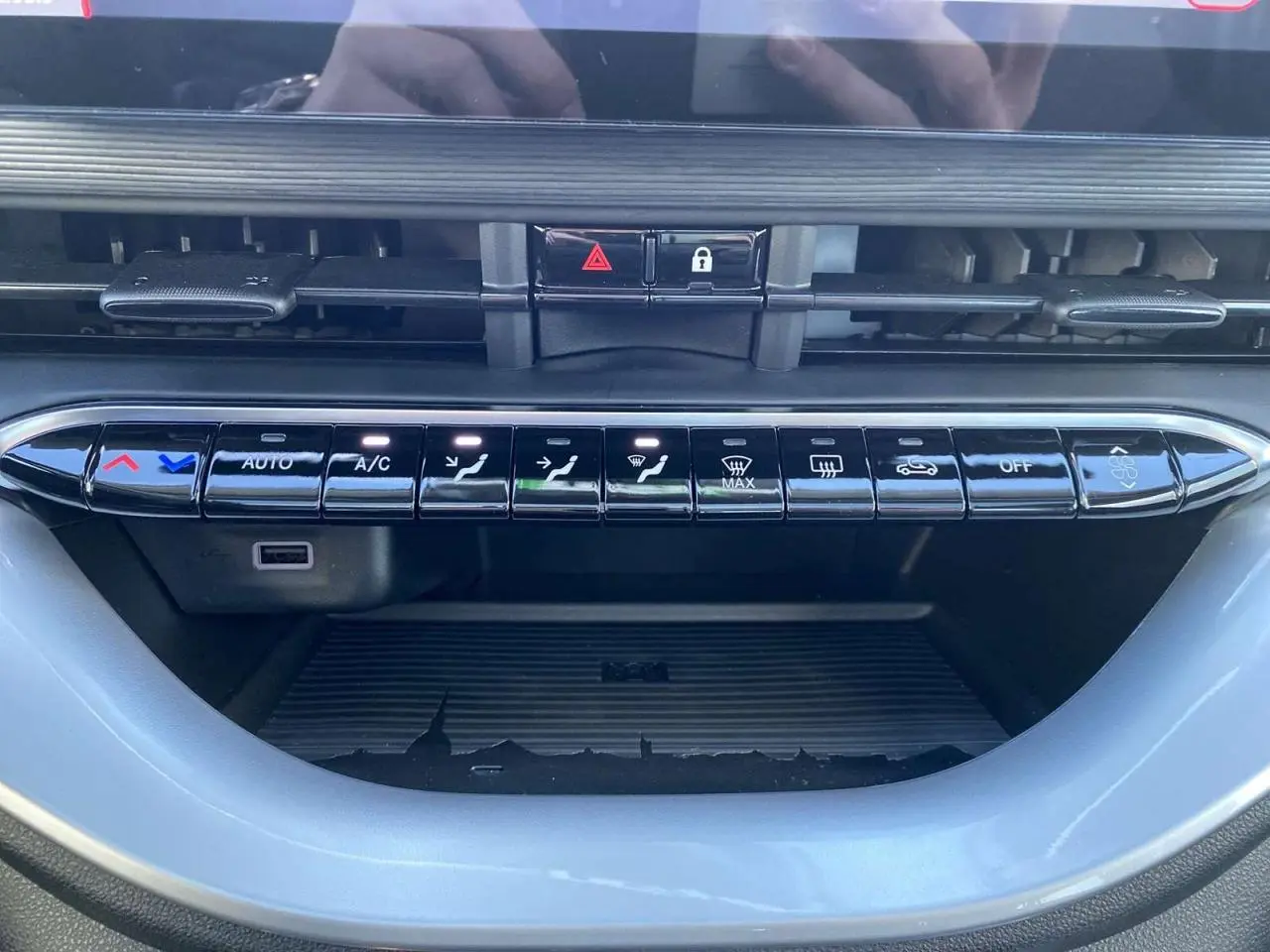 Panneau de commandes de climatisation noir brillant de la Fiat 500 électrique 2022 avec boutons tactiles et voyants allumés.