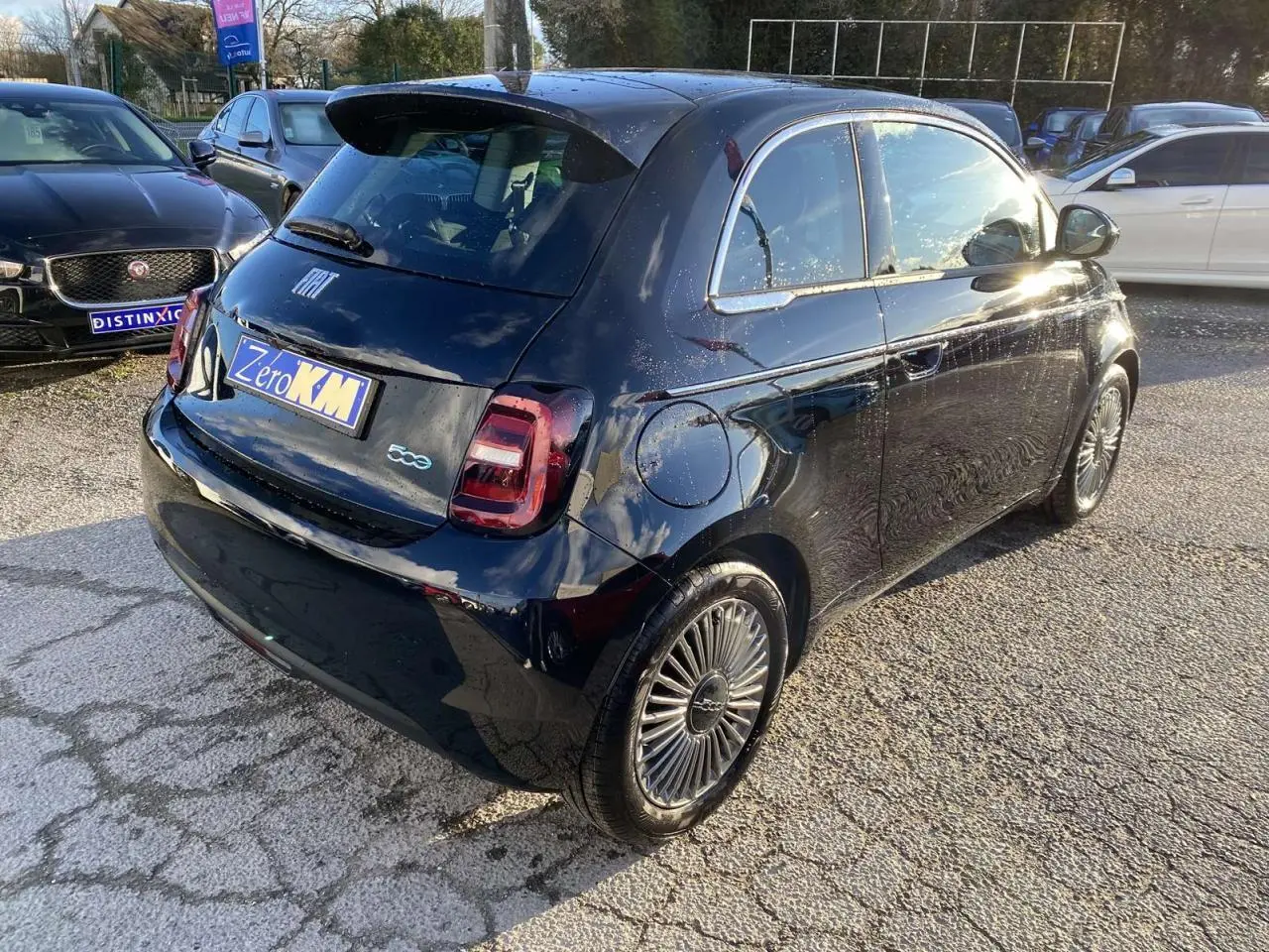 Fiat 500 électrique noire vue 3/4 arrière droit, avec jantes stylisées et poignées de portes discrètes.