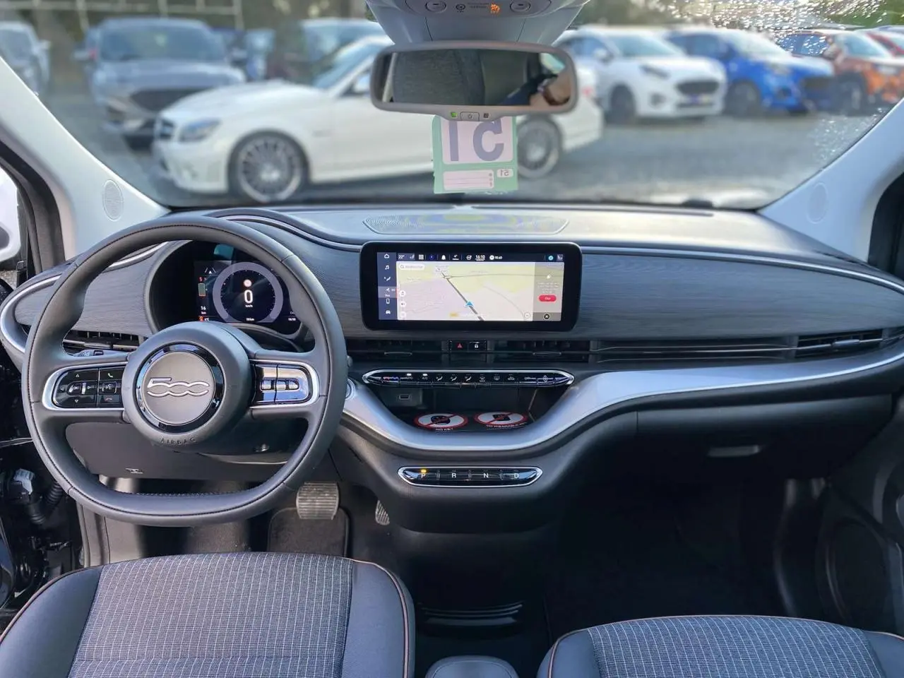 Vue intérieure avant de la FIAT 500 électrique noire 2022, tableau de bord moderne avec écran tactile et volant multifonction.