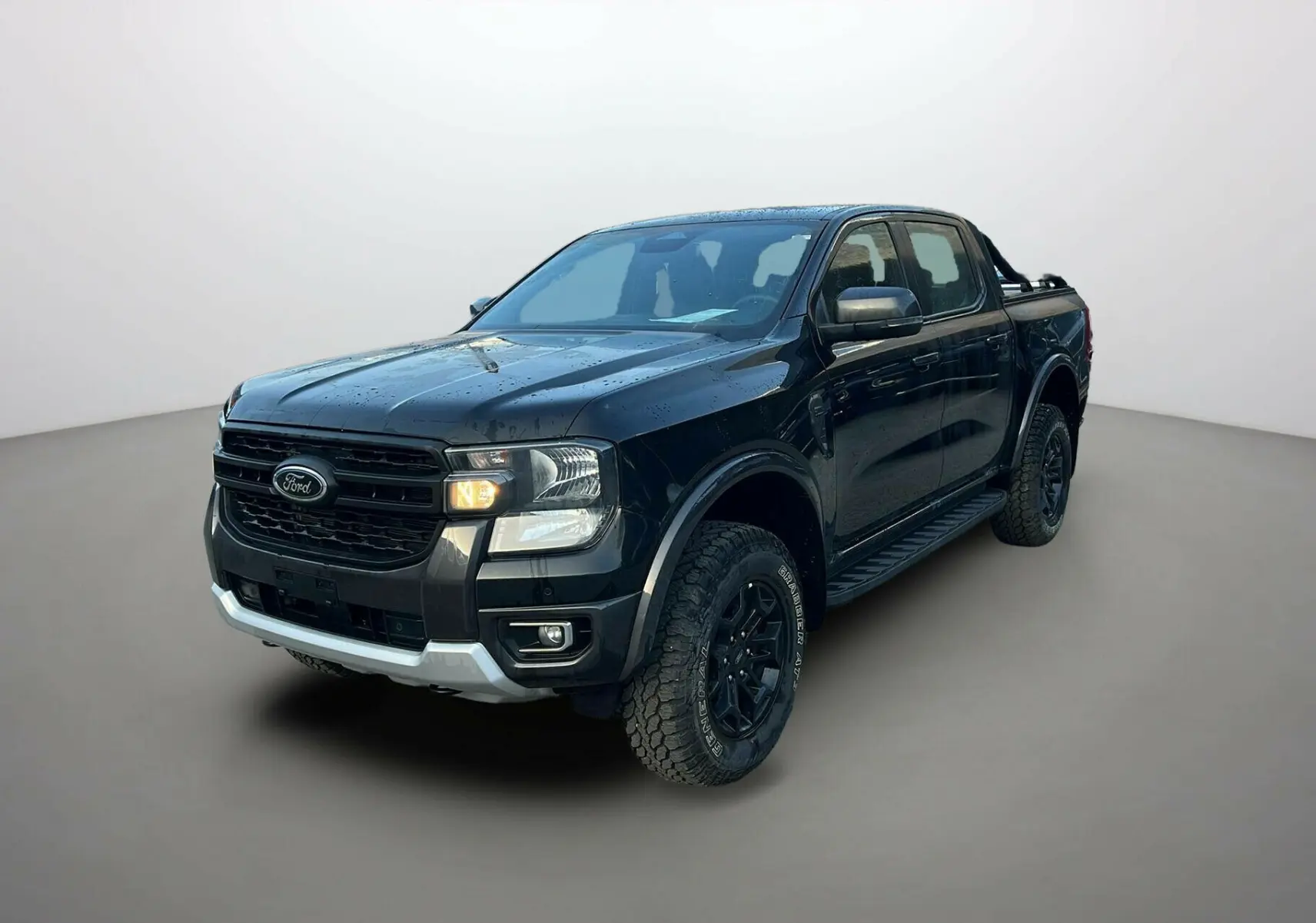 Ford Ranger 2025 noir shadow en 3/4 avant droit, avec calandre noire et pneus tout-terrain marqués.