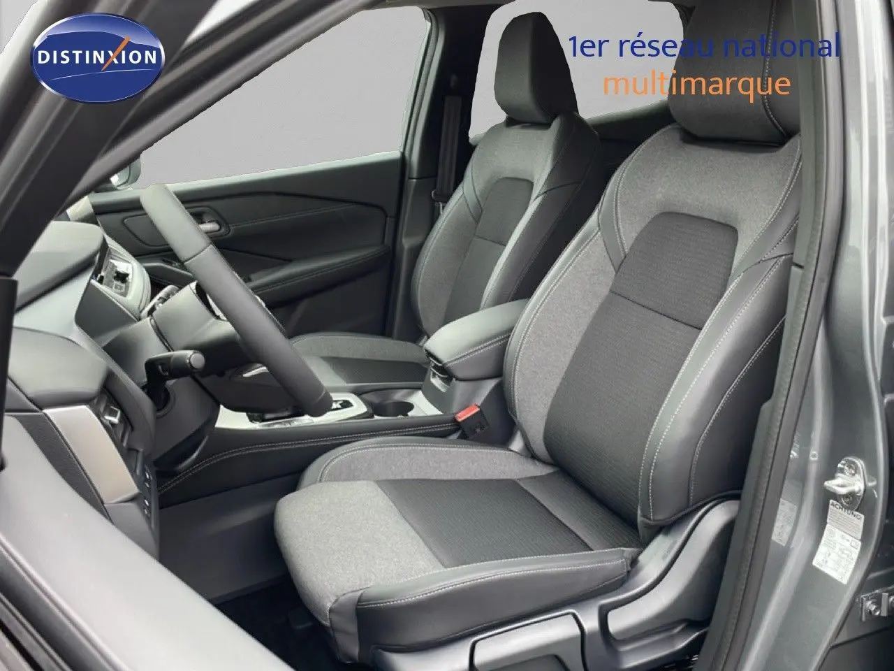 Vue intérieure côté conducteur du Nissan Qashqai 2025 gris squale métal, sièges tissu et cuir gris avec coutures contrastées.