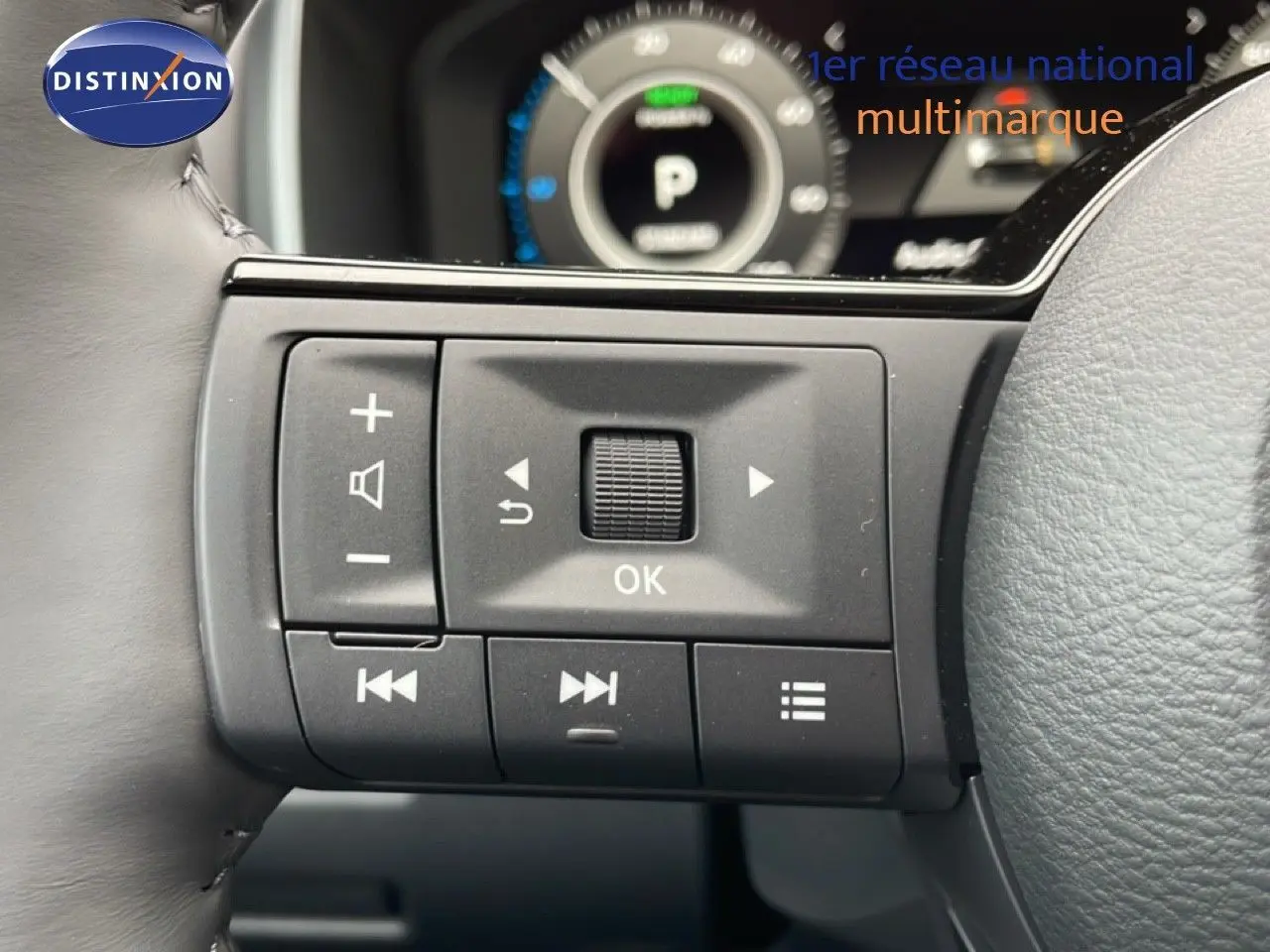 Gros plan sur les commandes multifonctions à gauche du volant du Nissan Qashqai 2025 gris squale métal, tableau de bord en arrière-plan flou.