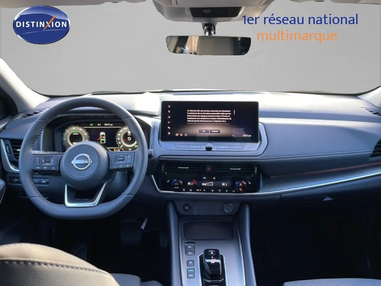 Vue intérieure du tableau de bord du Nissan Qashqai 2025 gris argile, avec volant multifonction et écran tactile central.