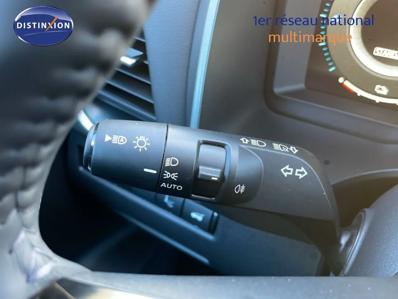 Gros plan sur la commande des feux et clignotants à gauche du volant du Nissan Qashqai gris argile 2025.