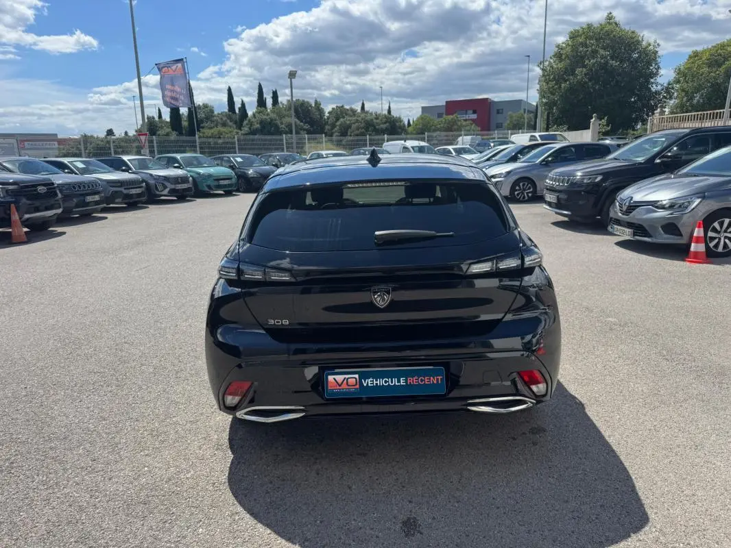Vue arrière d'une Peugeot 308 Hybrid 136 noire, avec feux LED et double sortie d'échappement chromée visible.