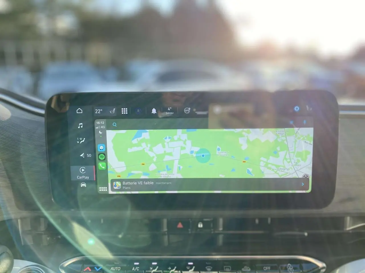 Écran tactile central affichant la navigation et l'alerte batterie faible dans l'habitacle d'une Fiat 500 électrique noire.
