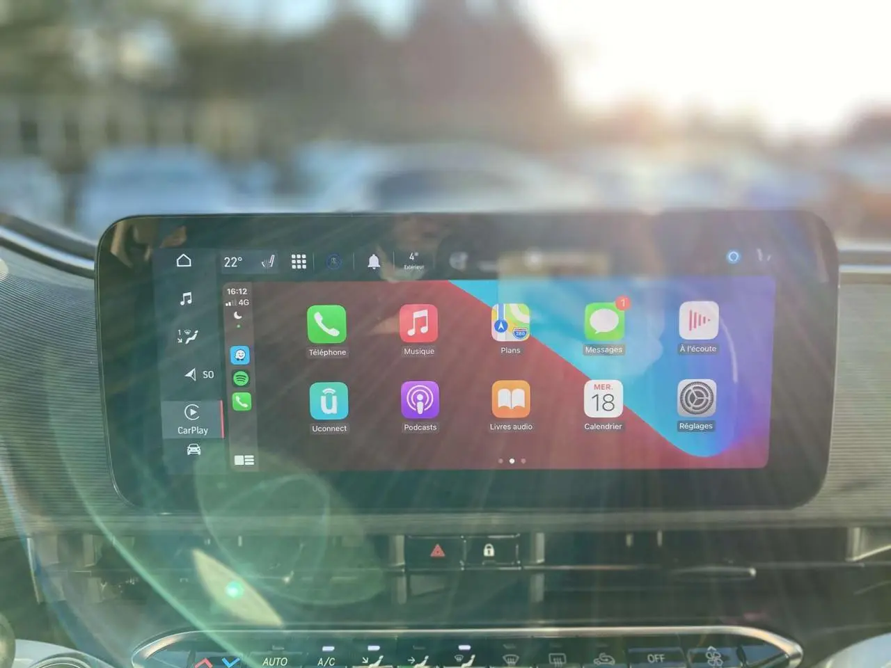 Écran tactile central de la FIAT 500 électrique 2022 affichant Apple CarPlay avec reflets lumineux à l'avant.