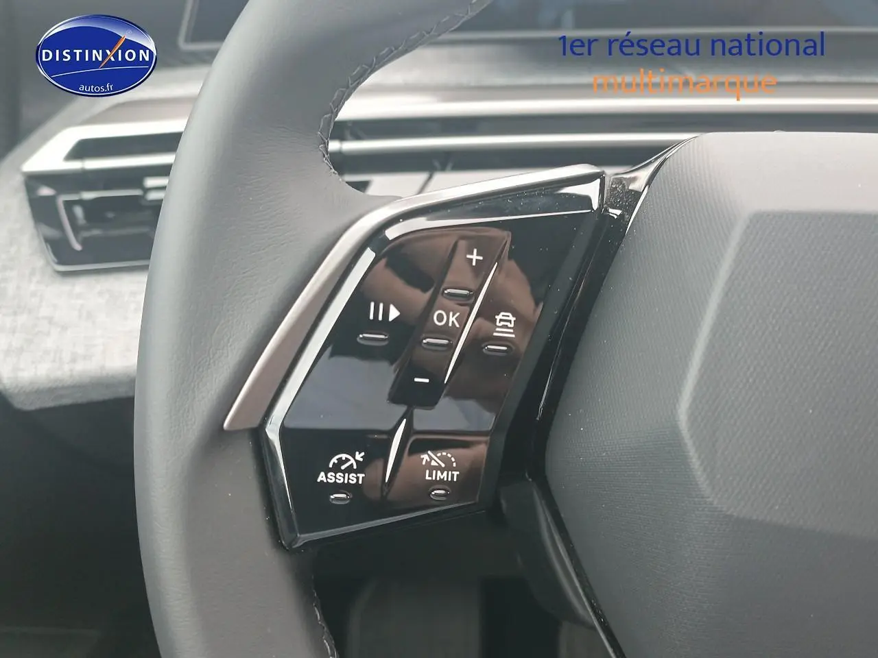 Gros plan sur les commandes multifonctions au volant côté gauche du Peugeot 5008 gris artense, intérieur moderne.