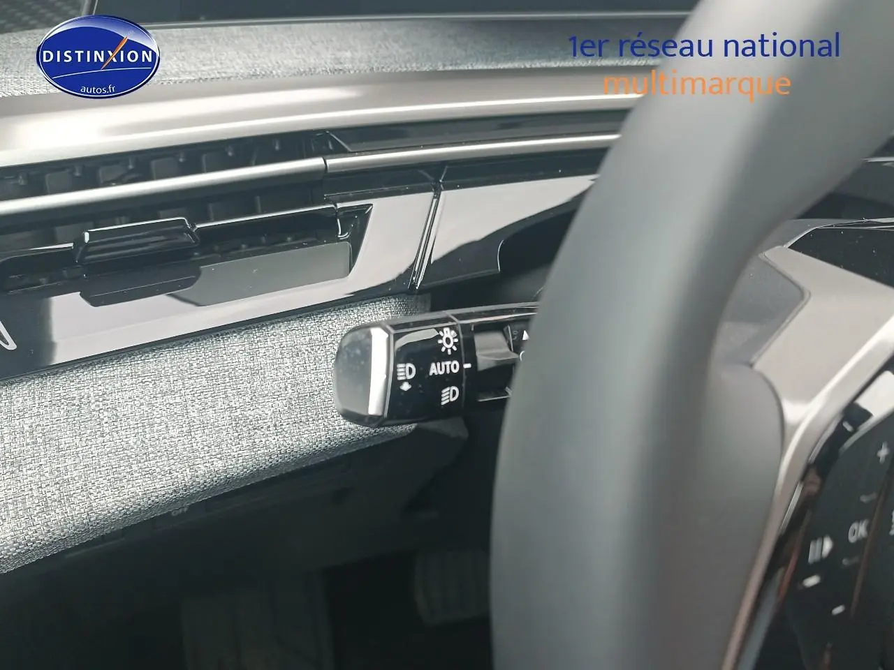 Gros plan sur la commande des phares à gauche du volant dans l’habitacle gris clair du Peugeot 5008 Hybrid 145 allure 2025.