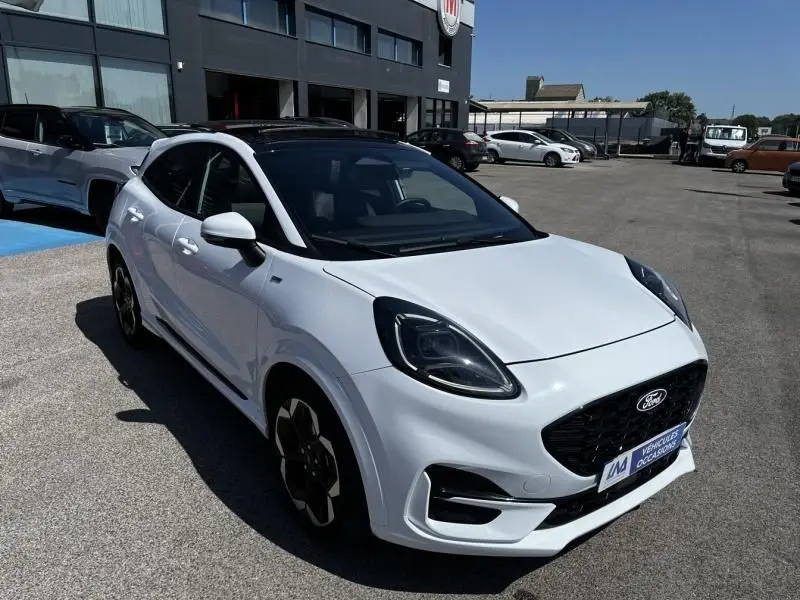 Ford Puma blanc 2025 en 3/4 avant droit, toit noir, calandre noire et jantes spécifiques ST-Line X visibles.