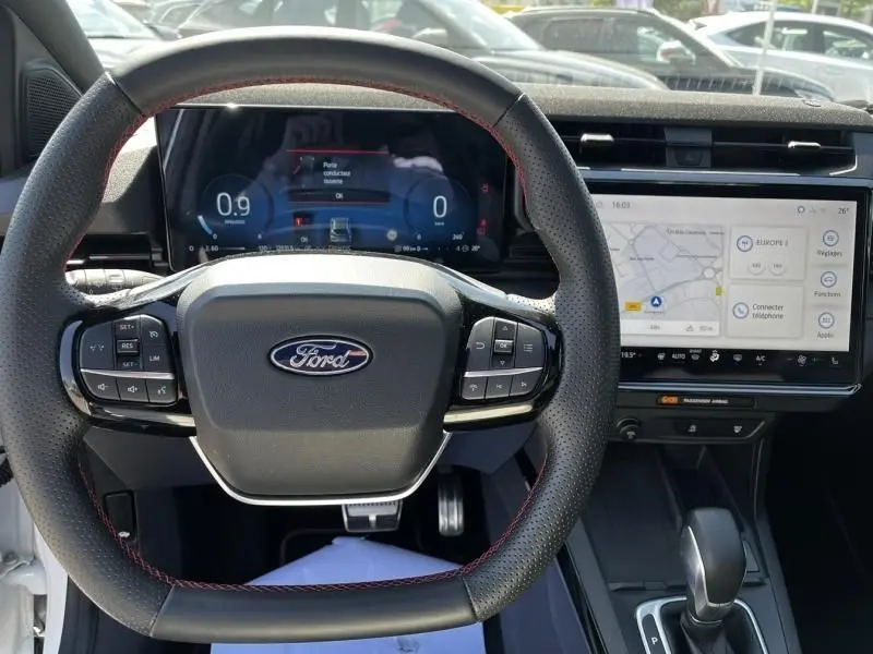 Vue intérieure centrée sur le volant Ford avec tableau de bord numérique et écran tactile du Ford Puma blanc 2025.