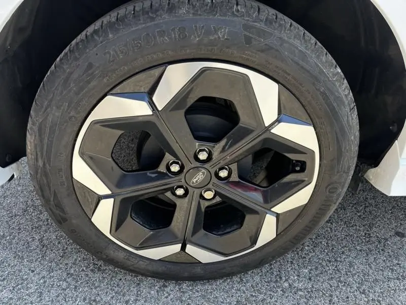Gros plan sur la roue avant droite du Ford Puma blanc 2025, jante alliage noire et argentée au design hexagonal.
