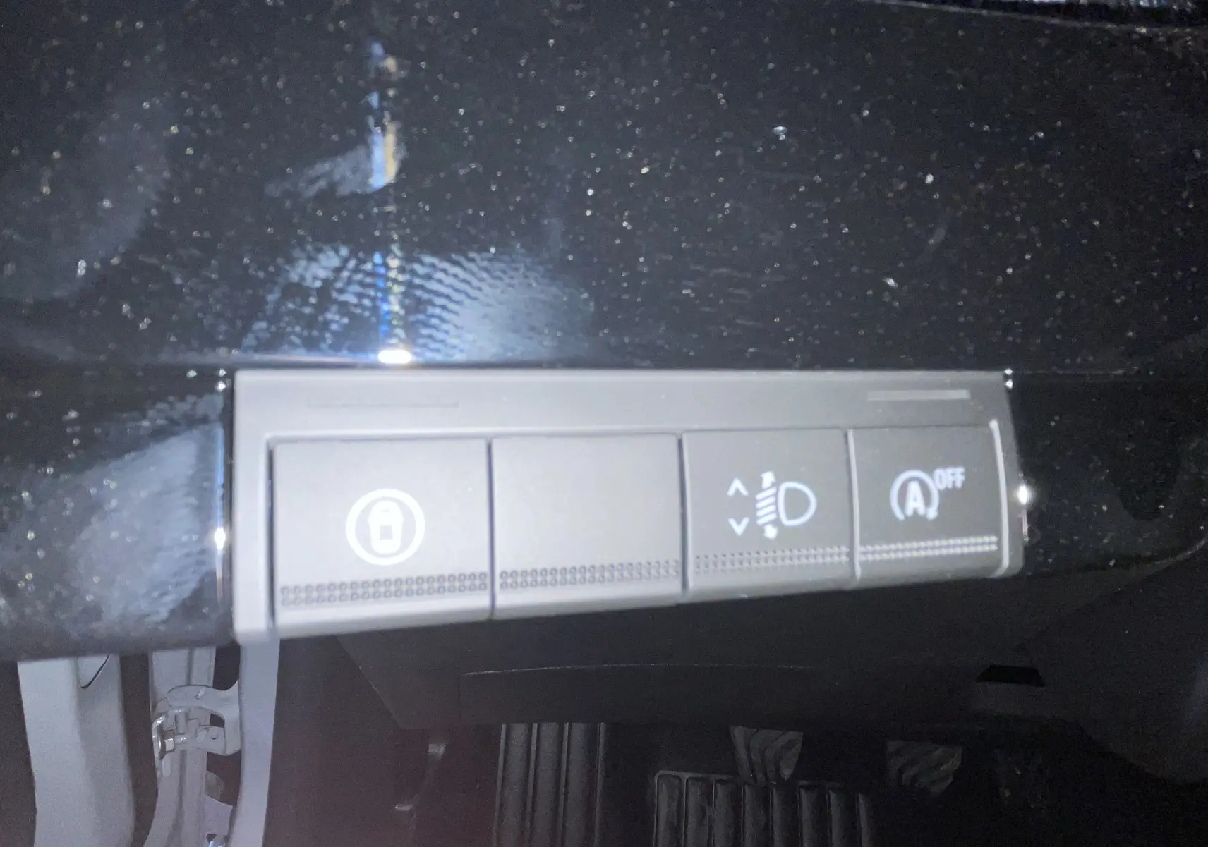 Gros plan sur les commandes de réglage des phares et désactivation du start-stop dans l’habitacle noir d’une Renault Clio VI gris Rafale.