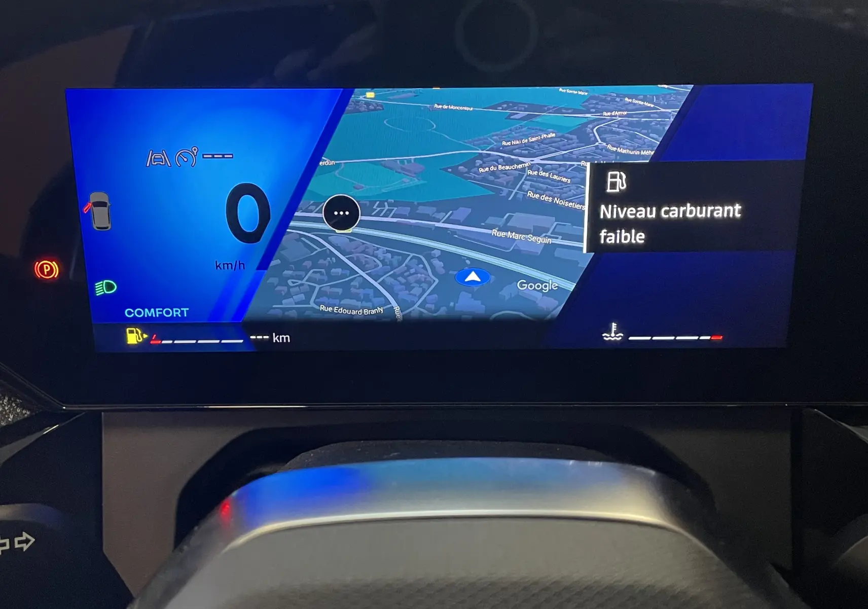 Tableau de bord numérique de Renault Clio VI TCe 115ch, affichant navigation GPS et alerte niveau carburant faible.