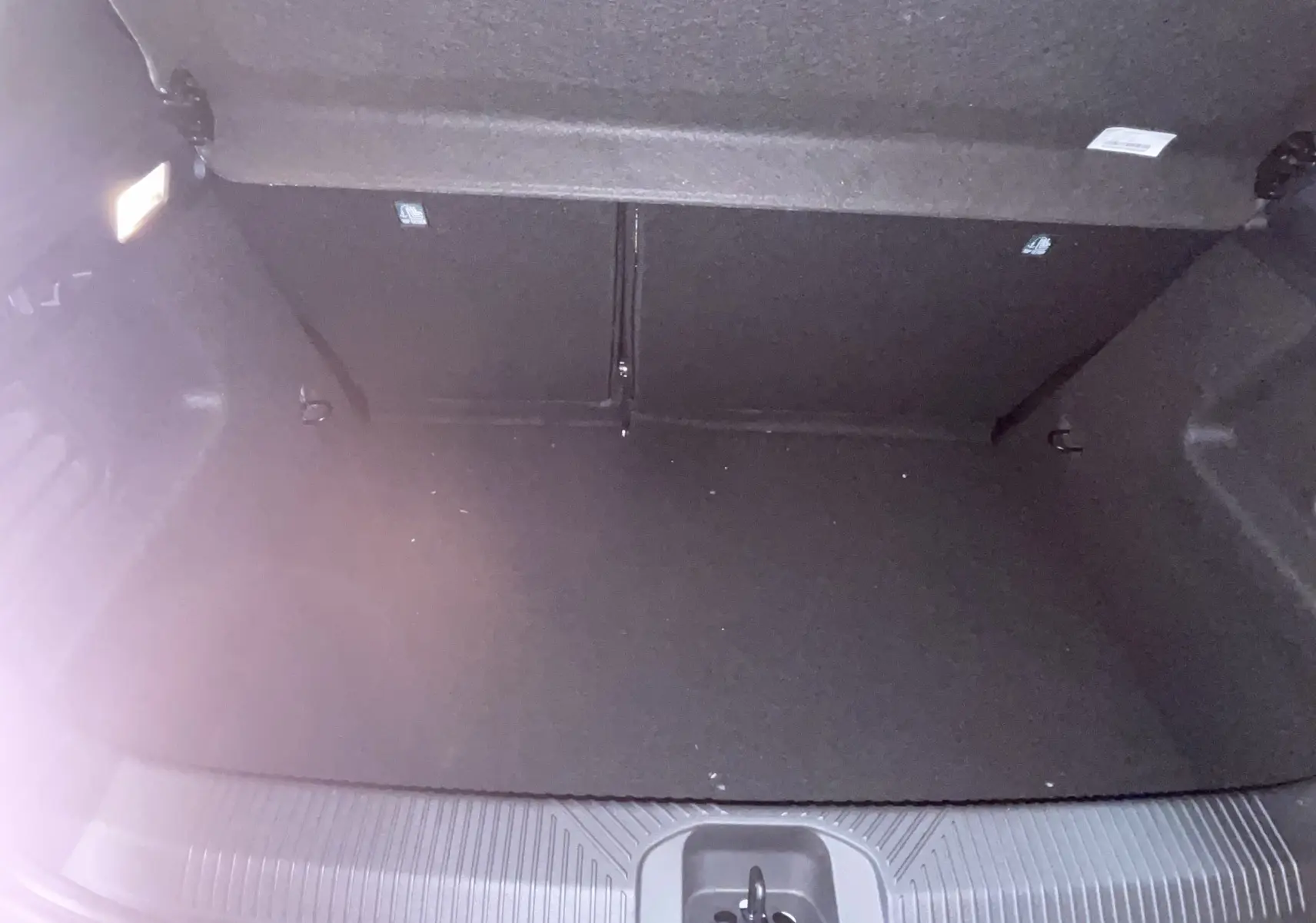 Coffre ouvert de la Renault Clio VI TCe 115ch Techno 2026, vue intérieure, revêtement noir et éclairage latéral.