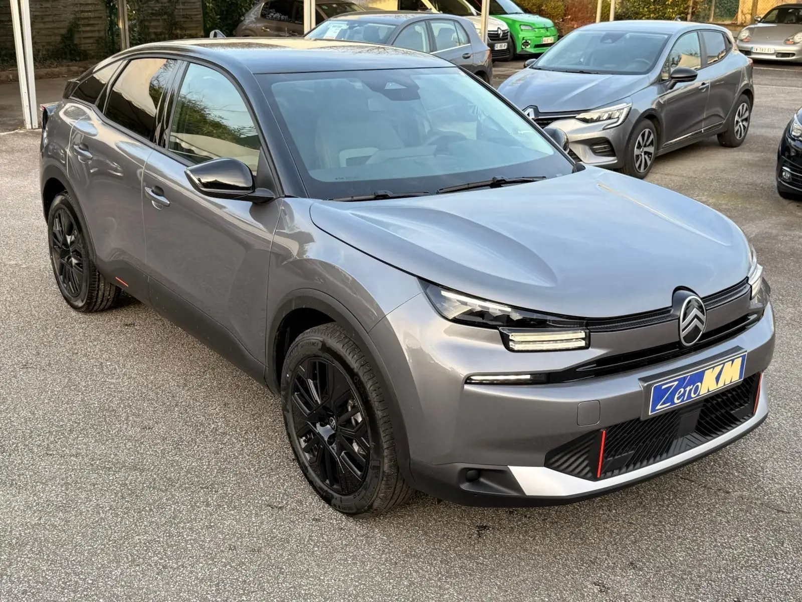 Vue 3/4 avant gauche d'une Citroën C4 hybride 2025 gris Mercury avec jantes noires et signature lumineuse LED distinctive.