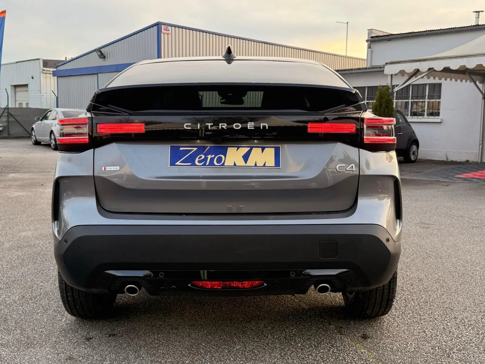 Vue arrière du Citroën C4 hybride gris Mercury avec feux LED allumés et logo distinctif sur le hayon.