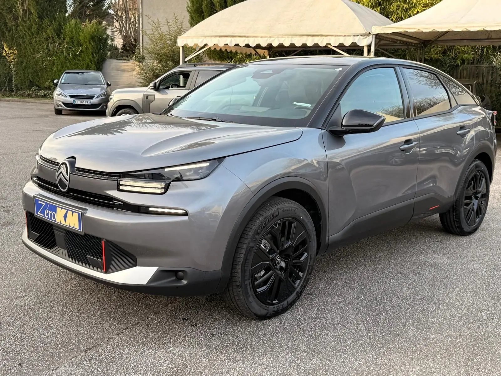 Citroën C4 hybride gris Mercury vue 3/4 avant droit avec jantes noires et signature lumineuse LED distinctive.