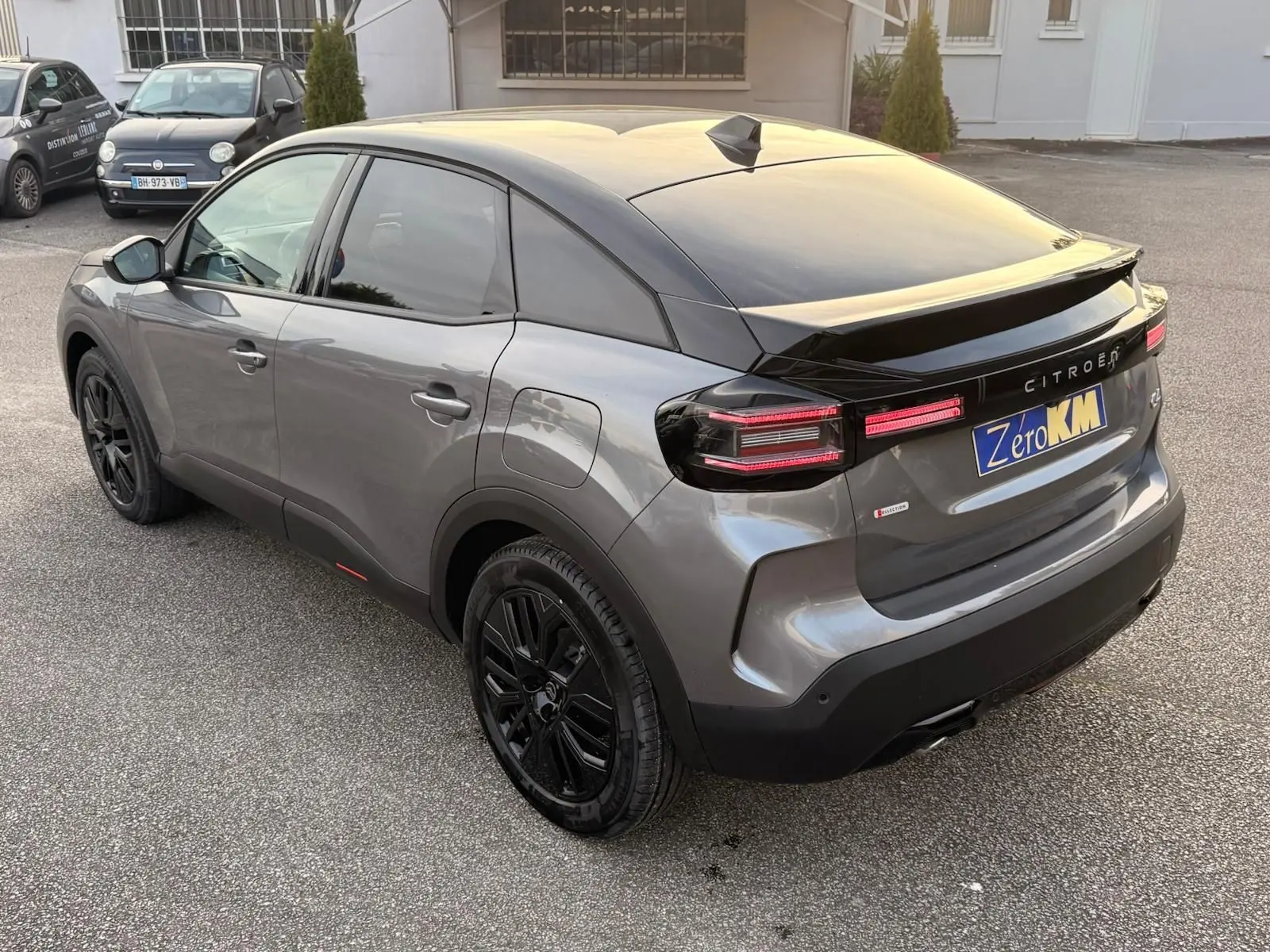 Vue 3/4 arrière droite d'une Citroën C4 hybride gris Mercury avec jantes noires et feux arrière LED distinctifs.