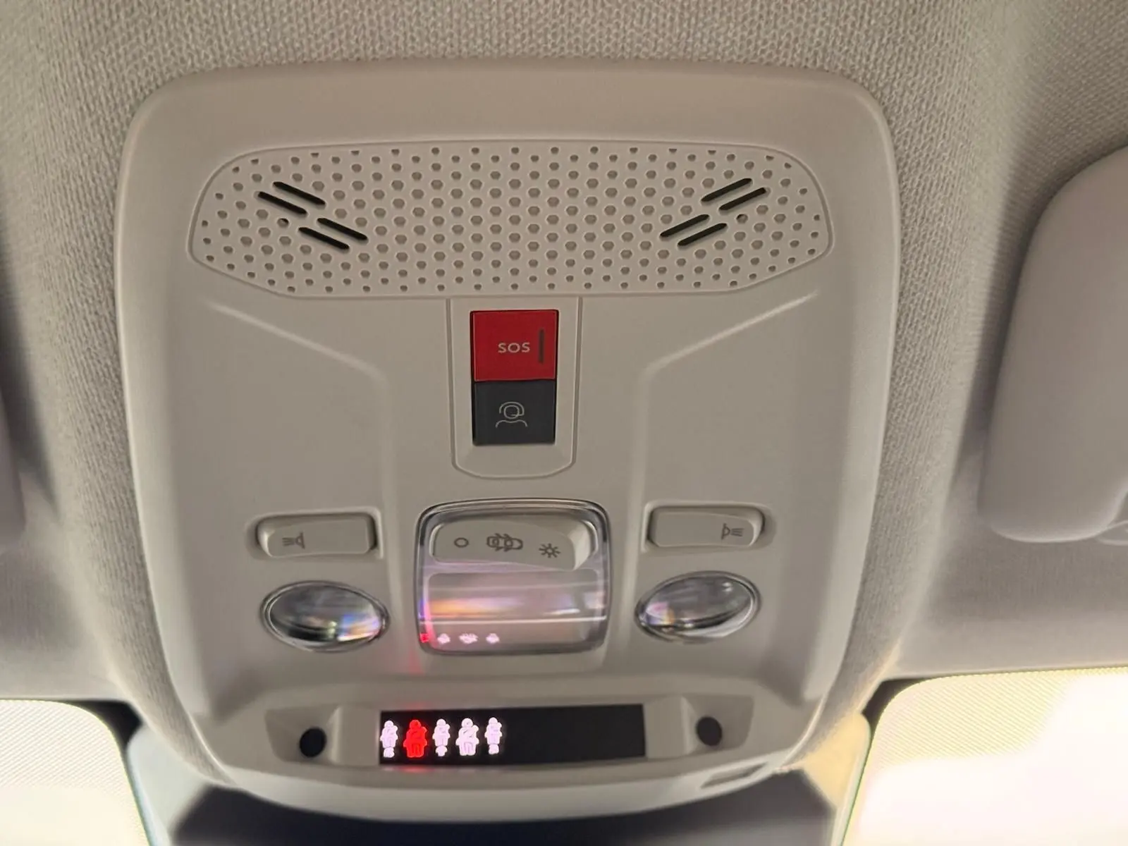Vue en gros plan du panneau de commandes au plafond intérieur du Citroën C4 gris Mercury, avec bouton SOS rouge et éclairage intégré.