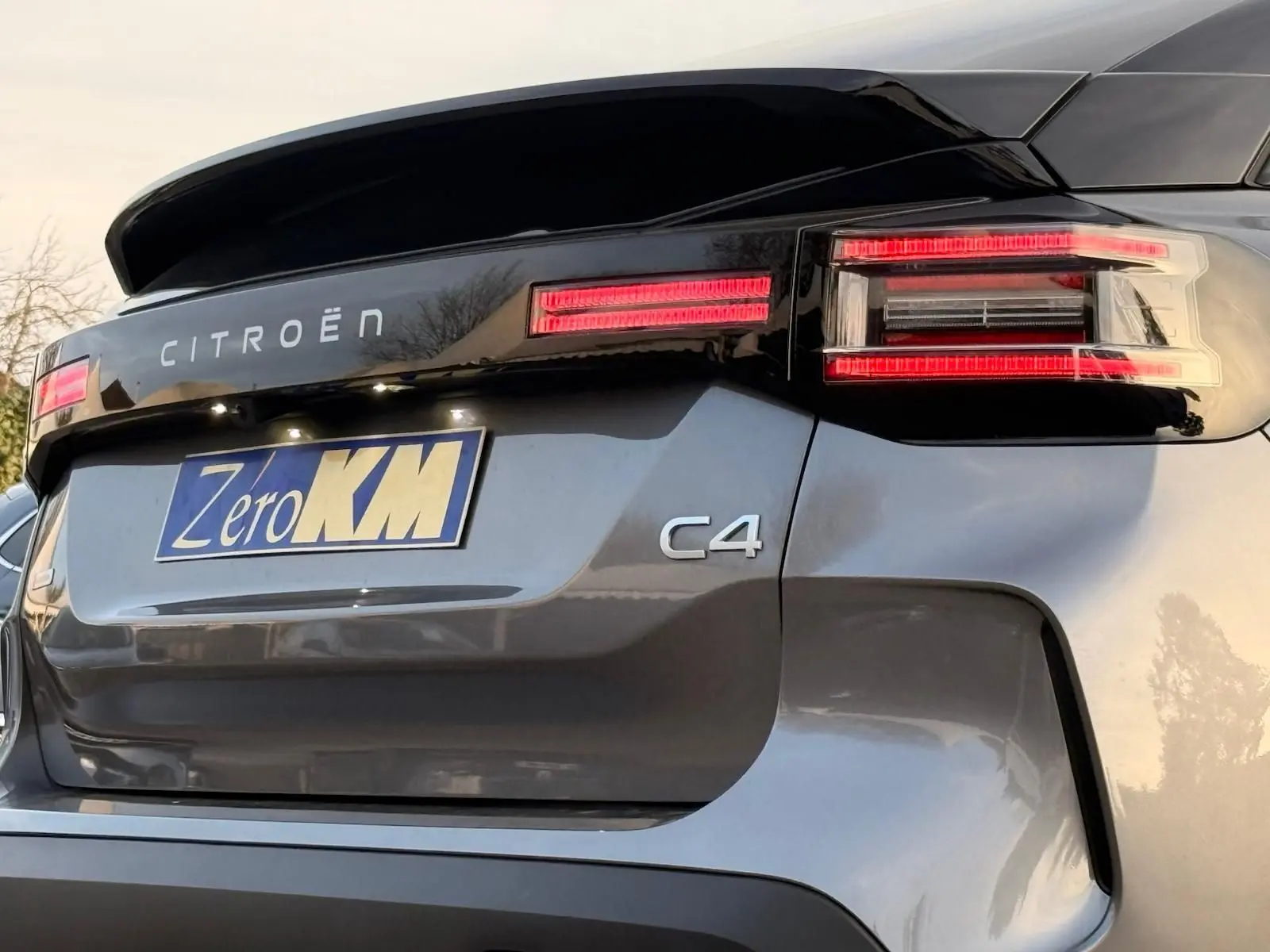 Vue 3/4 arrière droite d'une Citroën C4 gris Mercury avec feux arrière LED et logo distinctif sur hayon.