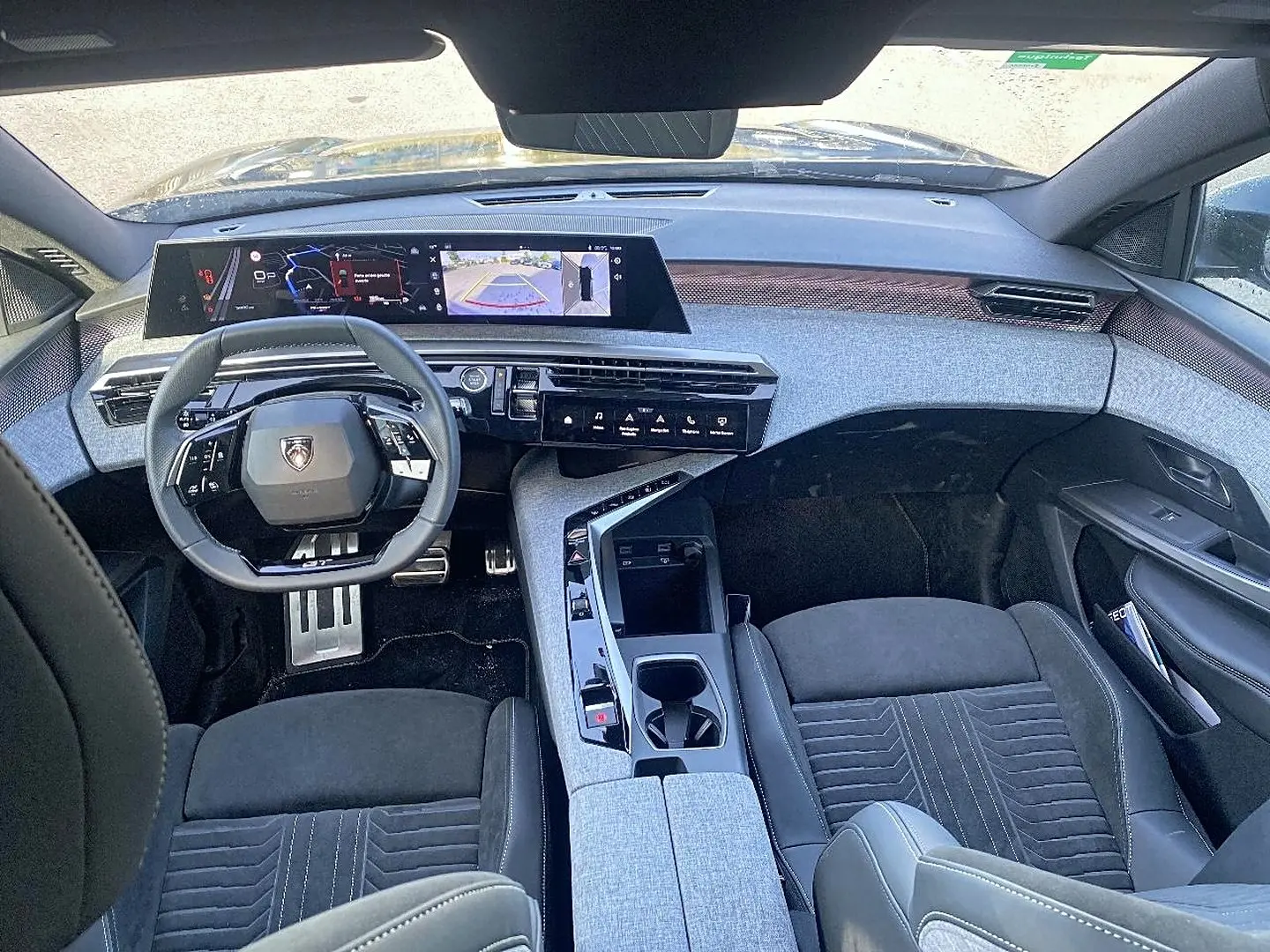 Vue intérieure avant du Peugeot 5008 Hybrid 145 GT e-dcs6 2025, tableau de bord moderne avec écran large et sièges noirs.