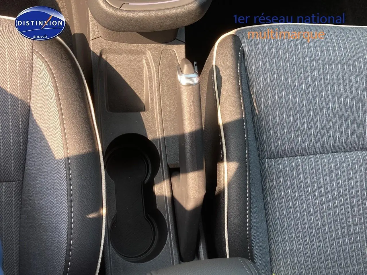 Vue plongeante sur l'accoudoir central et les sièges en tissu gris de la Renault Clio V 1.6 e-tech 145 techno.