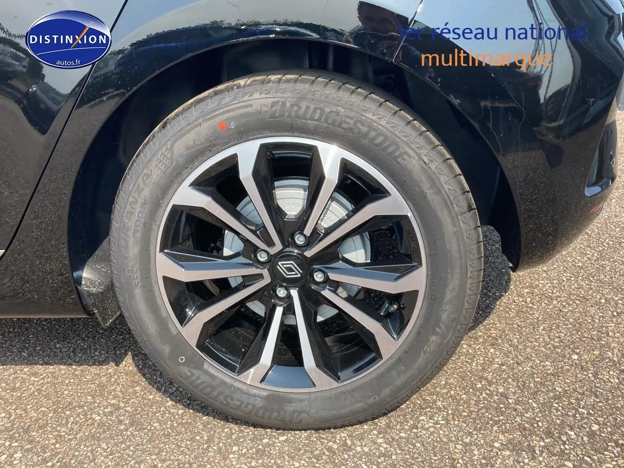 Gros plan sur la jante alu noire et argentée côté gauche d'une Renault Clio V noir étoile.