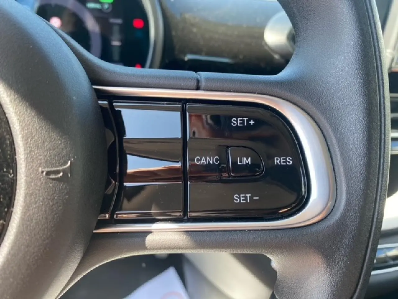 Gros plan sur les commandes de régulateur de vitesse au volant noir de la Fiat 500 électrique blanche de 2022.