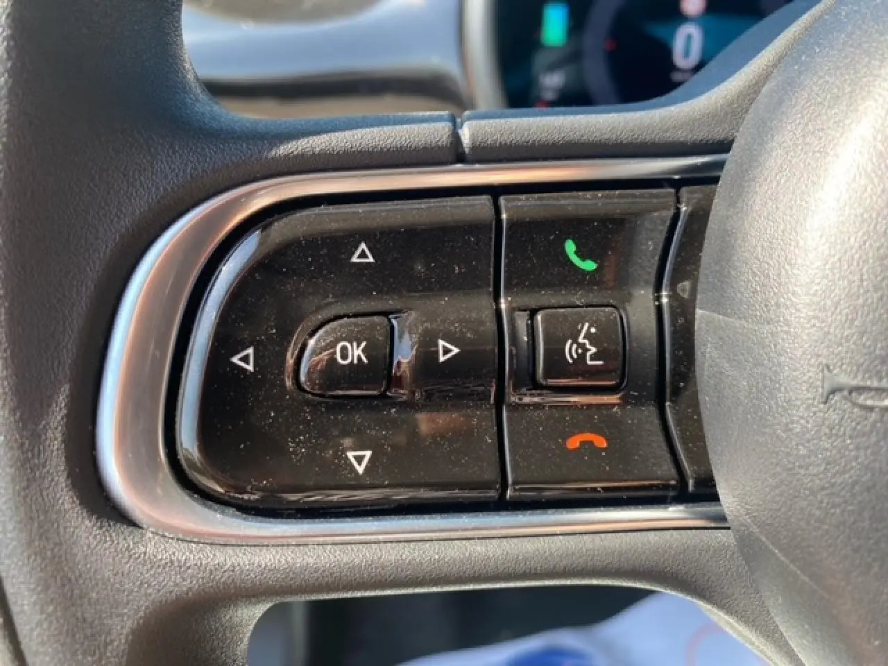 Gros plan sur les commandes multifonctions noires à gauche du volant de la Fiat 500 électrique blanche de 2022.