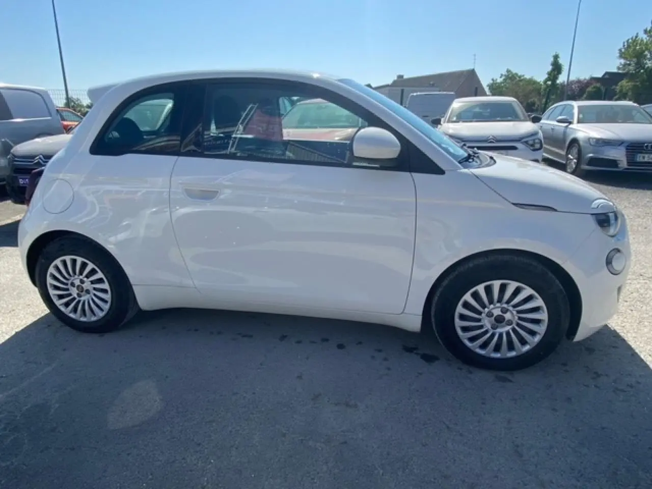 Profil côté gauche d'une FIAT 500 électrique blanche Ice White 2022 avec jantes alliage et peinture métallisée.