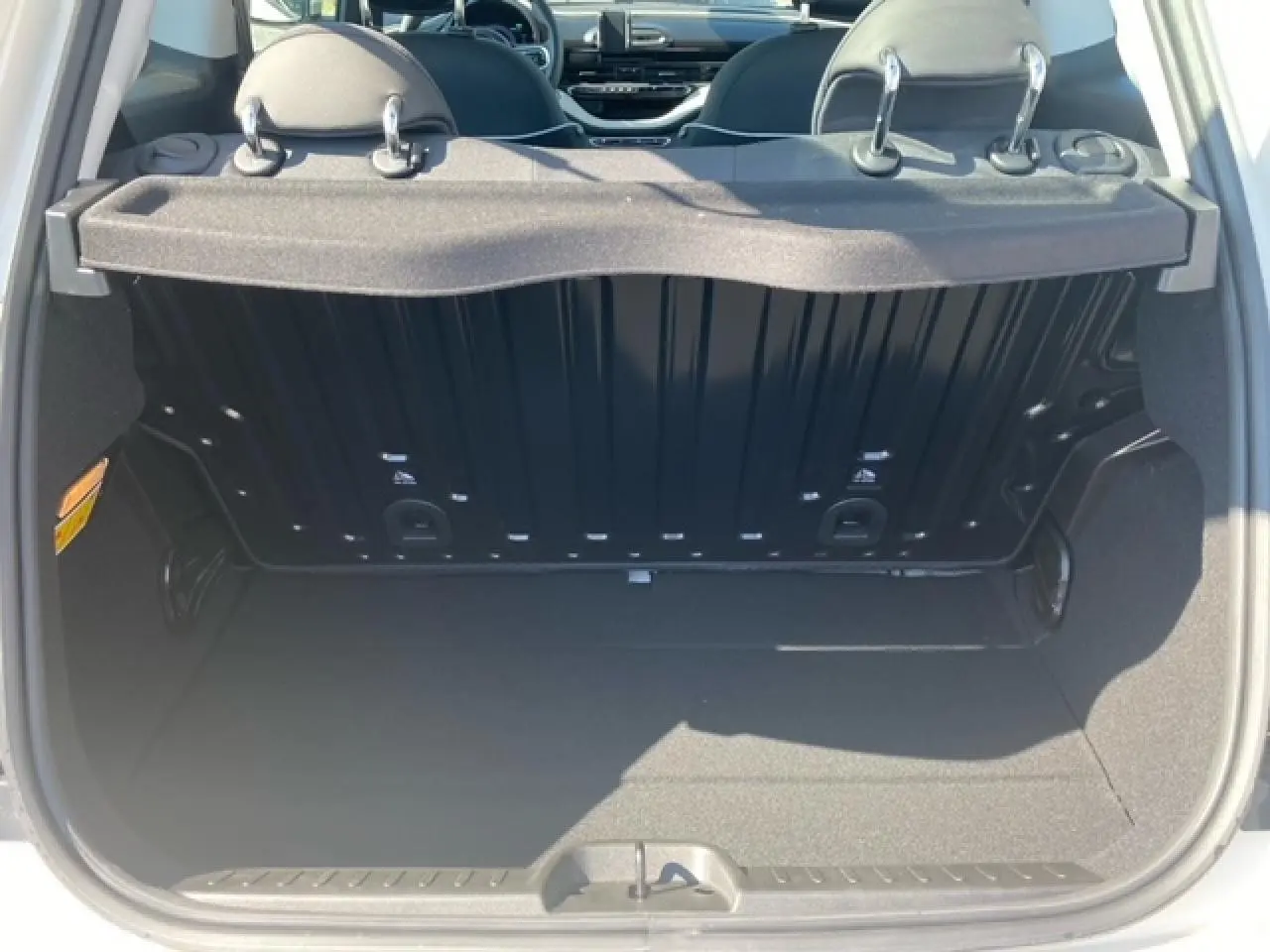 Coffre ouvert vu de l'arrière d'une FIAT 500 électrique blanche, montrant l'espace de chargement et l'intérieur arrière.
