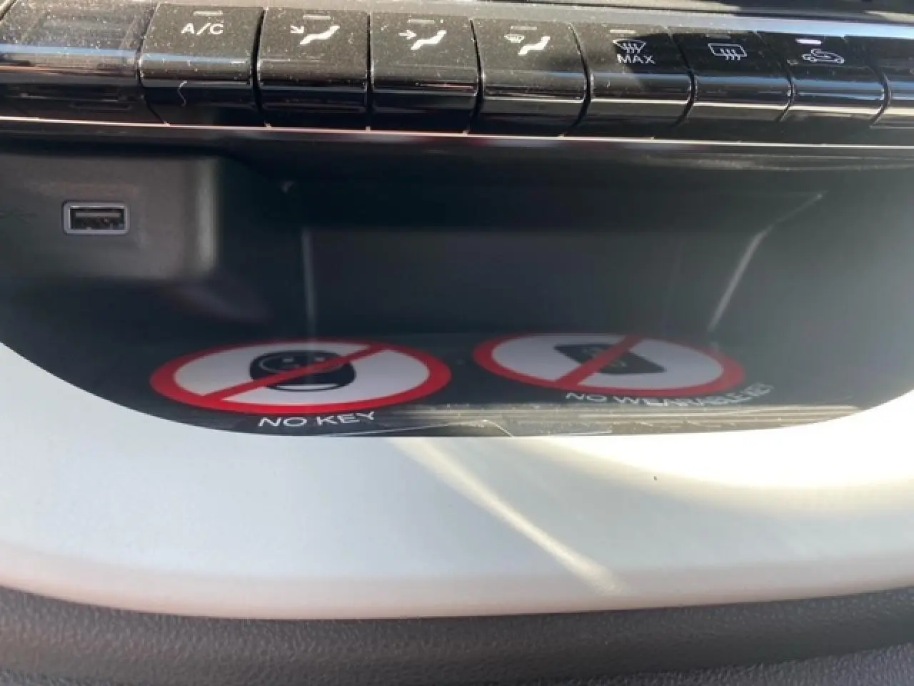 Vue rapprochée du compartiment de rangement intérieur blanc de la Fiat 500 électrique avec boutons de commande au-dessus.