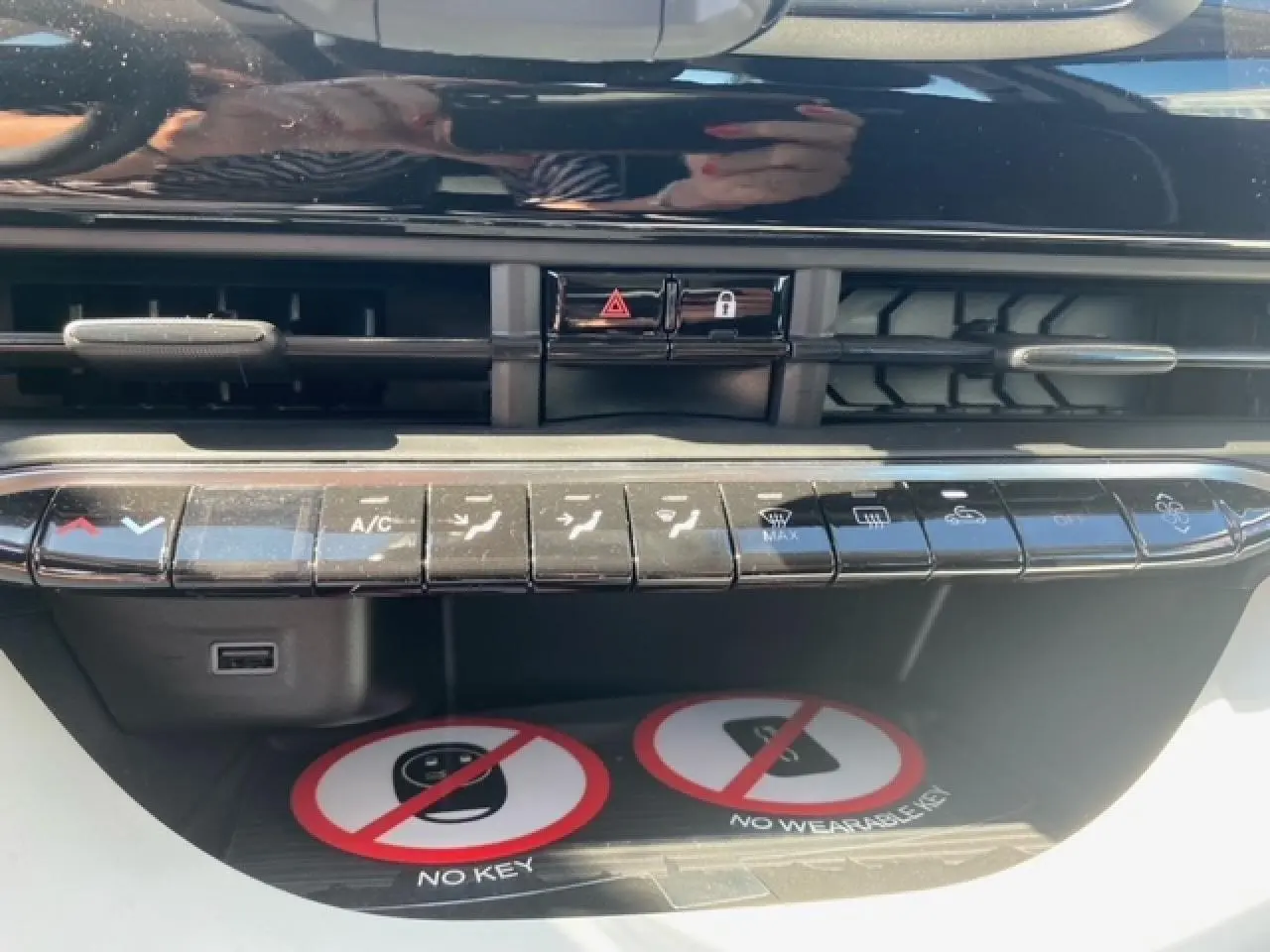 Gros plan sur la console centrale noire de la Fiat 500 électrique blanche, montrant les commandes de climatisation et ventilation.