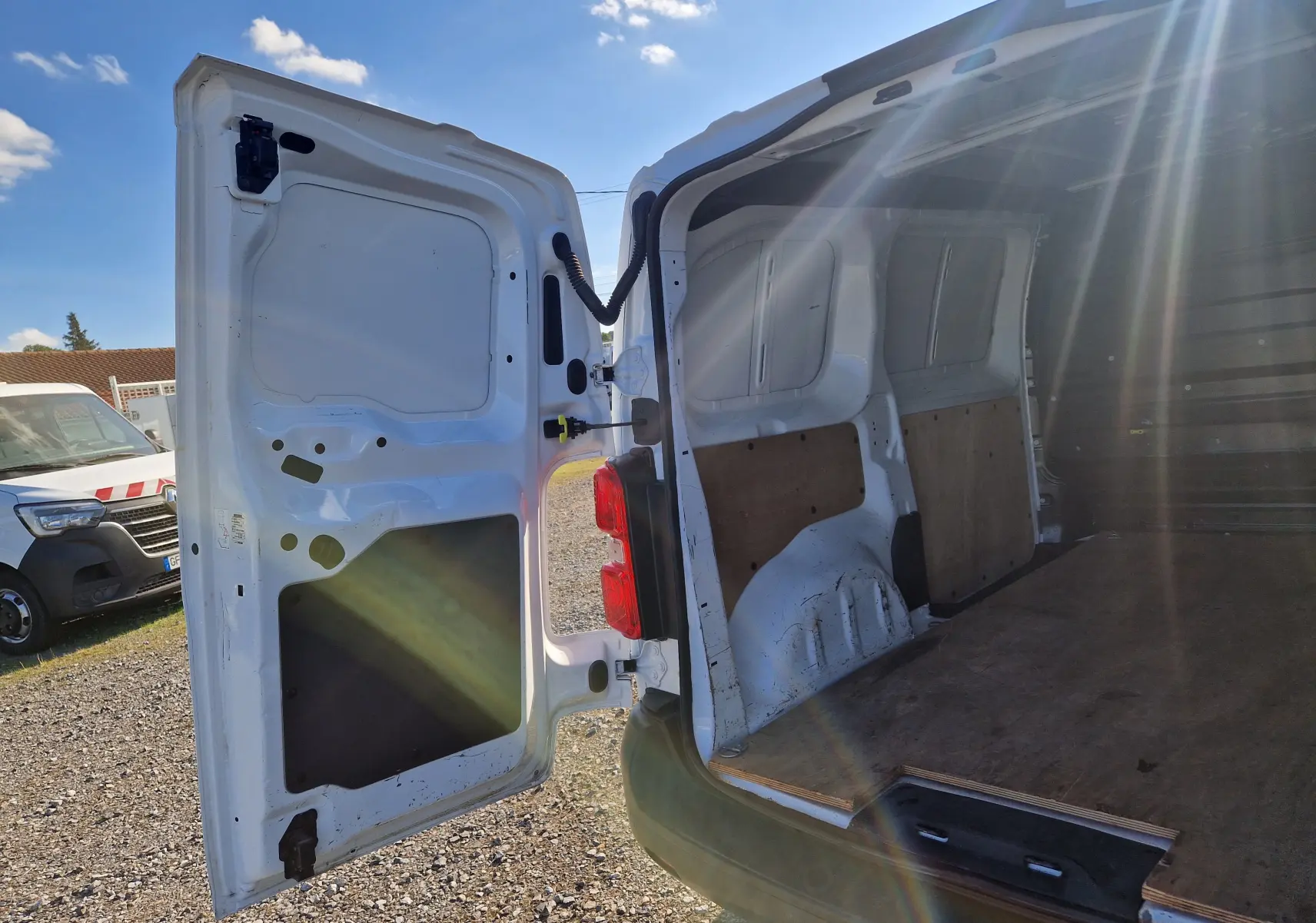 Vue arrière ouverte du Peugeot Expert Fourgon blanc 2020 montrant l'espace de chargement vide avec panneaux en bois.