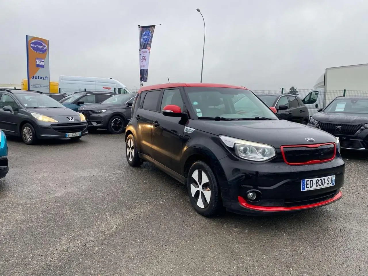 KIA Soul électrique noir avec toit rouge, vue 3/4 avant droit, détails rouges sur calandre et pare-chocs.