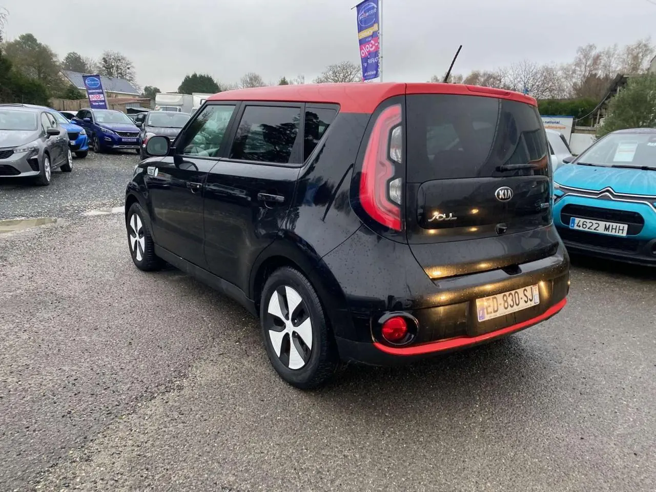 Vue 3/4 arrière droite d'une Kia Soul électrique noire avec toit rouge et jantes alliage 16 pouces.