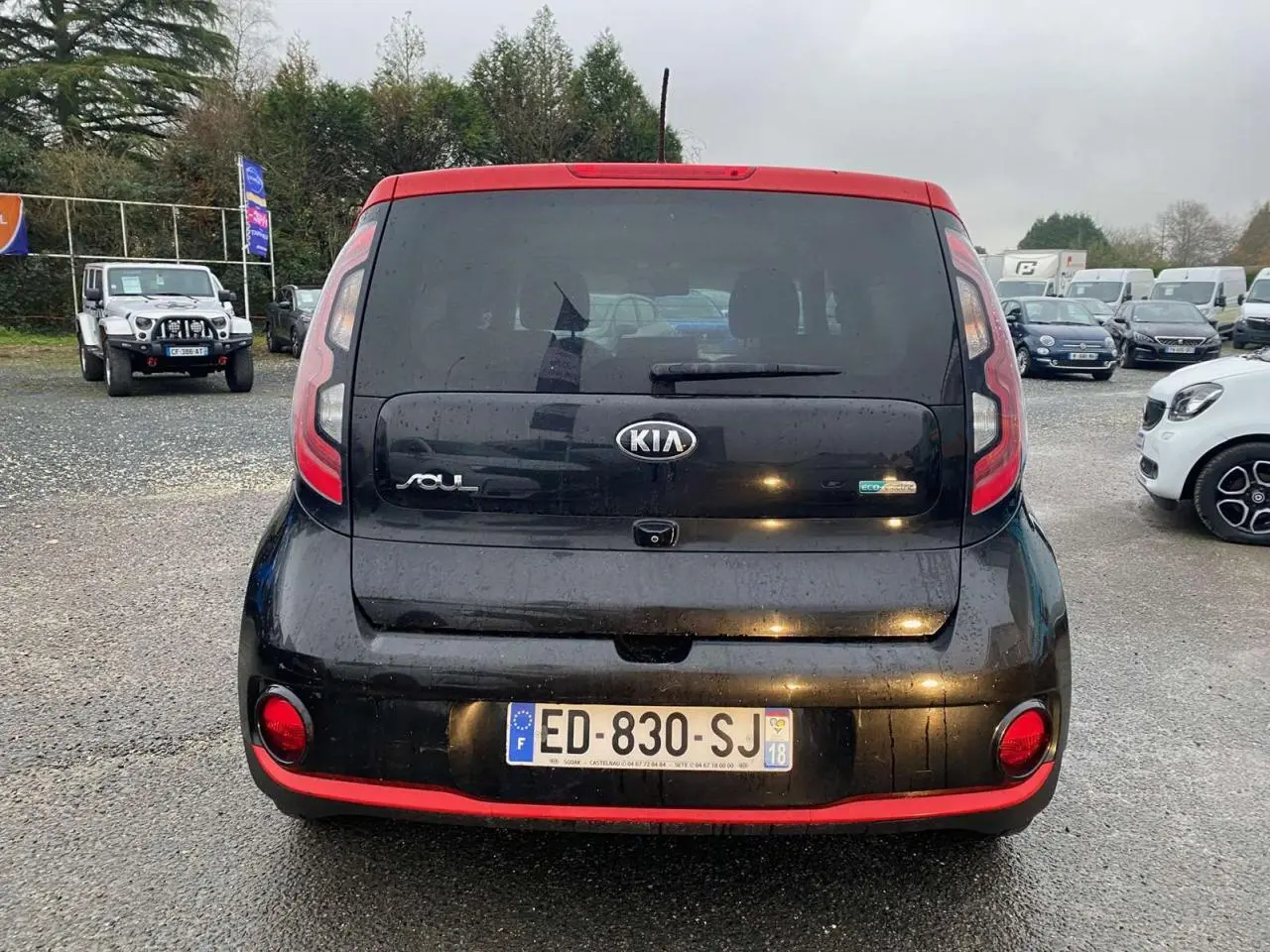 Vue arrière d'une KIA Soul électrique noire avec toit rouge et caméra de recul visible sur le hayon.