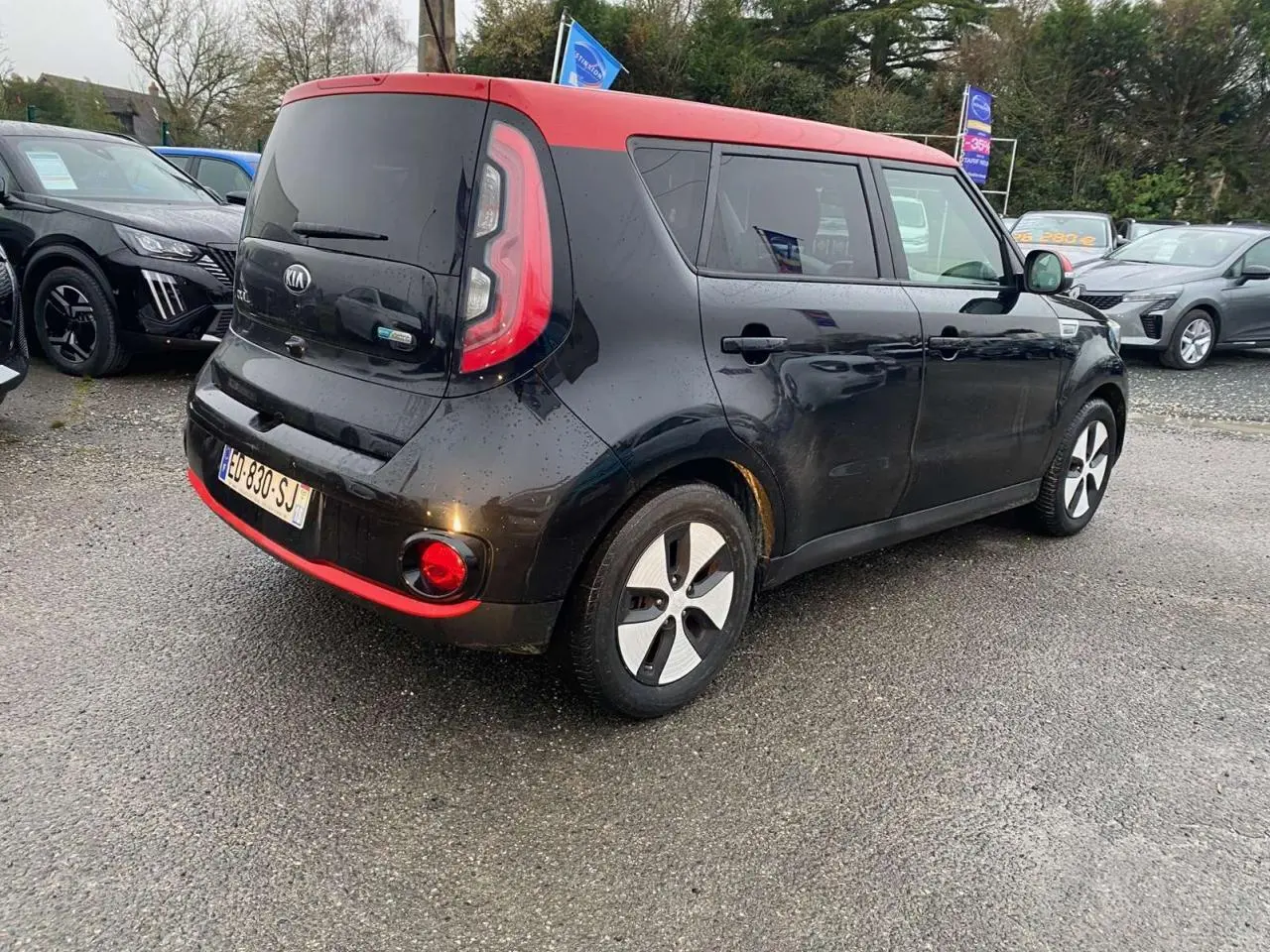Vue 3/4 arrière droite d'une KIA Soul électrique noire avec toit rouge et jantes alliage 16 pouces.