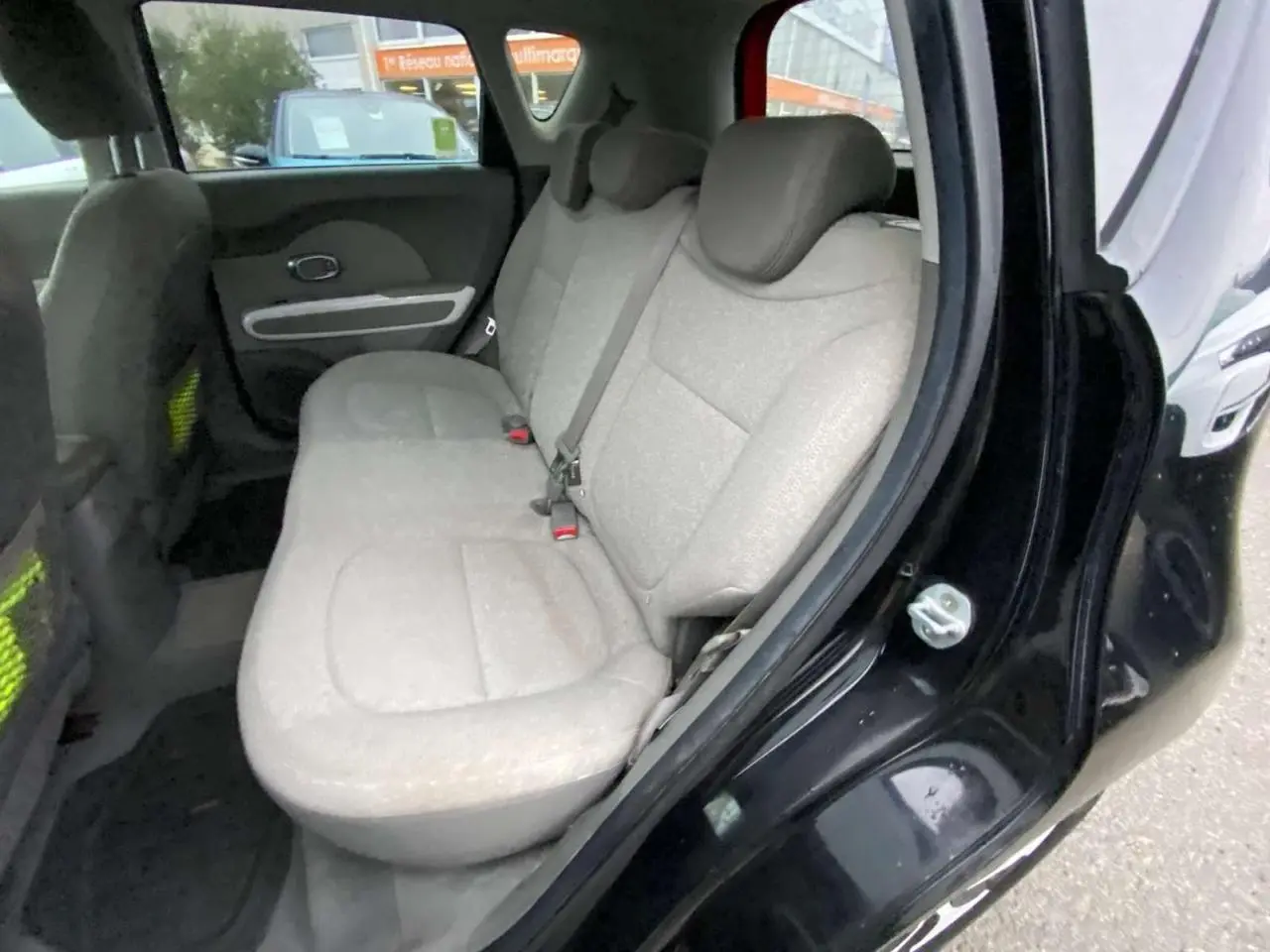 Vue intérieure côté gauche de la banquette arrière beige du KIA SOUL électrique noir avec porte ouverte.