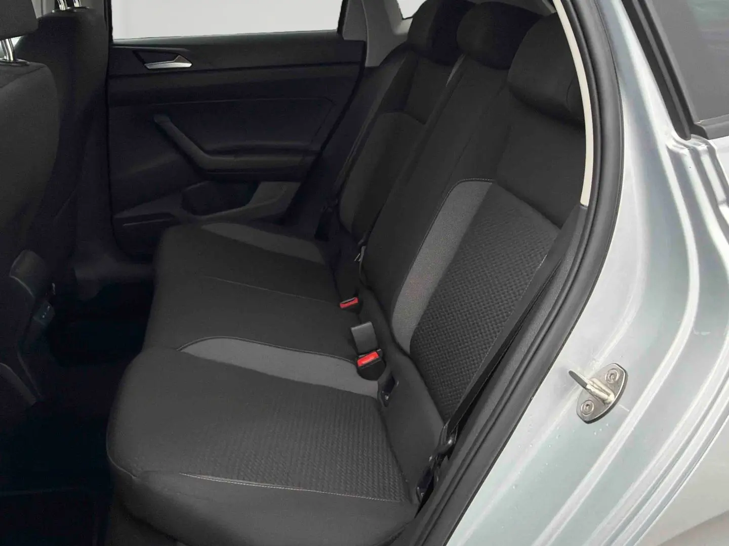 Vue côté droit de la banquette arrière noire et grise d'une Volkswagen Polo 2025 gris clair avec portière ouverte.