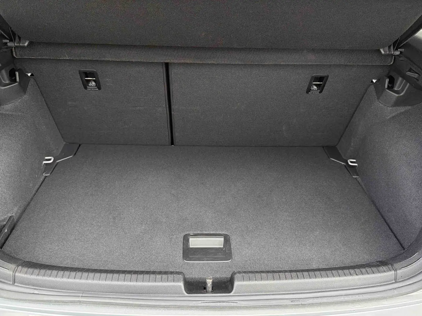 Coffre ouvert d’une Volkswagen Polo grise 2025, vue plongeante sur l’espace de chargement vide et propre.