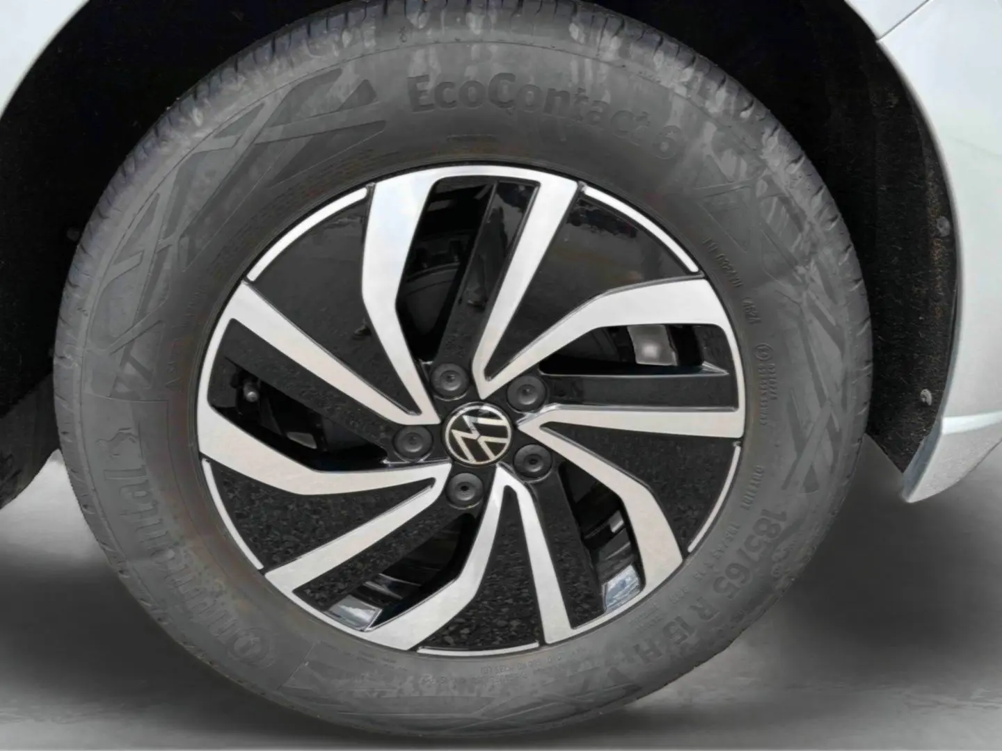Gros plan sur la jante alliage 15 pouces bicolore avec logo Volkswagen au centre sur une Polo grise.