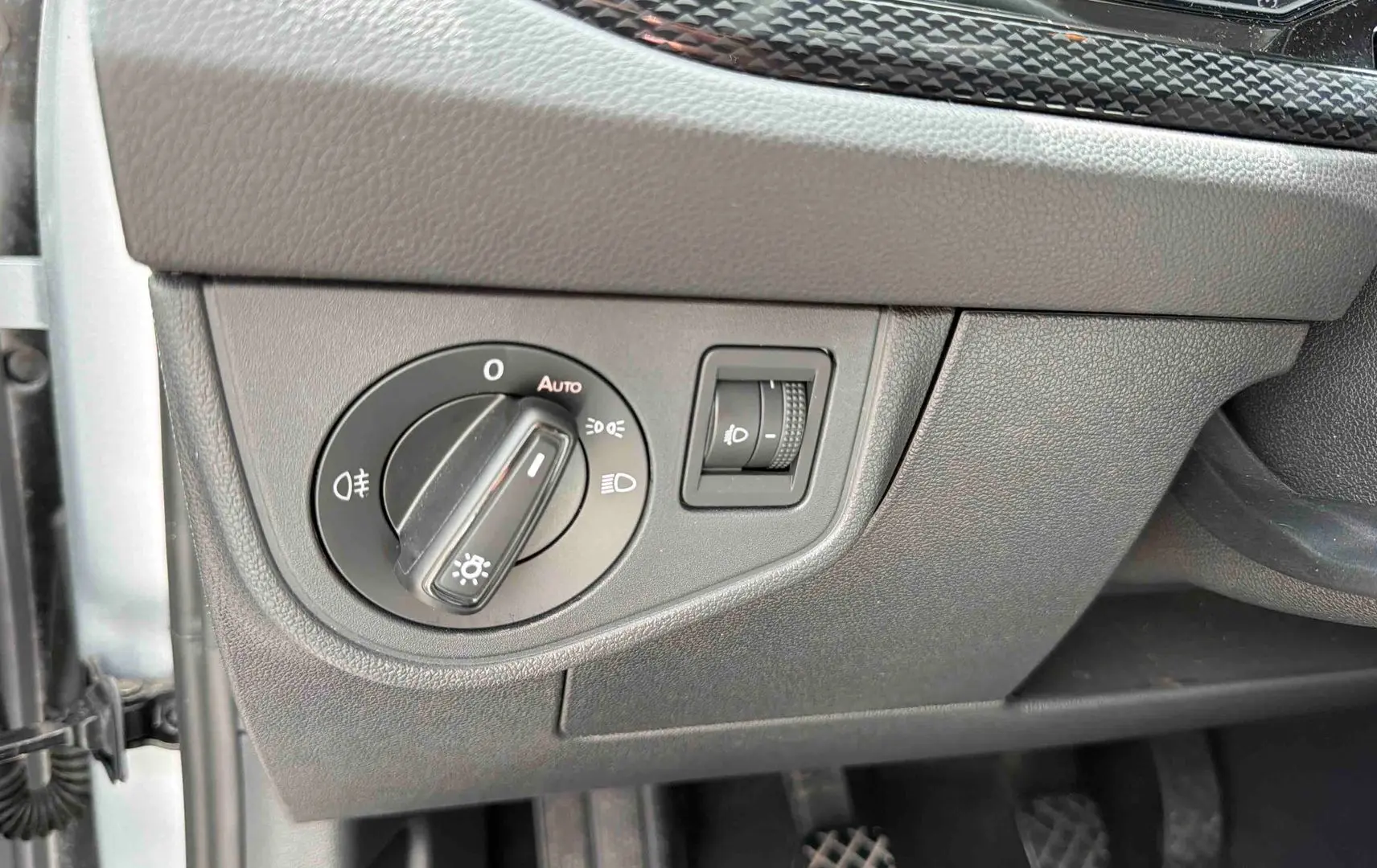 Gros plan sur le panneau de commande des phares dans l'habitacle d'une Volkswagen Polo grise, côté conducteur.