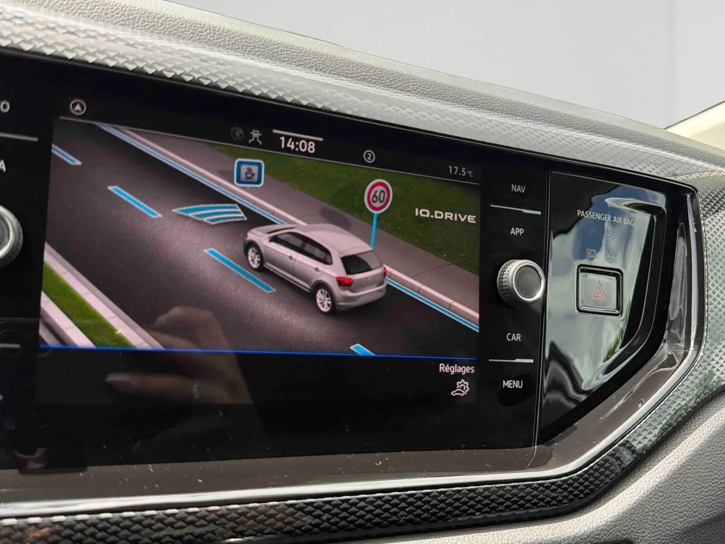 Écran tactile intérieur affichant la caméra de recul d'une Volkswagen Polo grise vue en 3/4 arrière sur route.