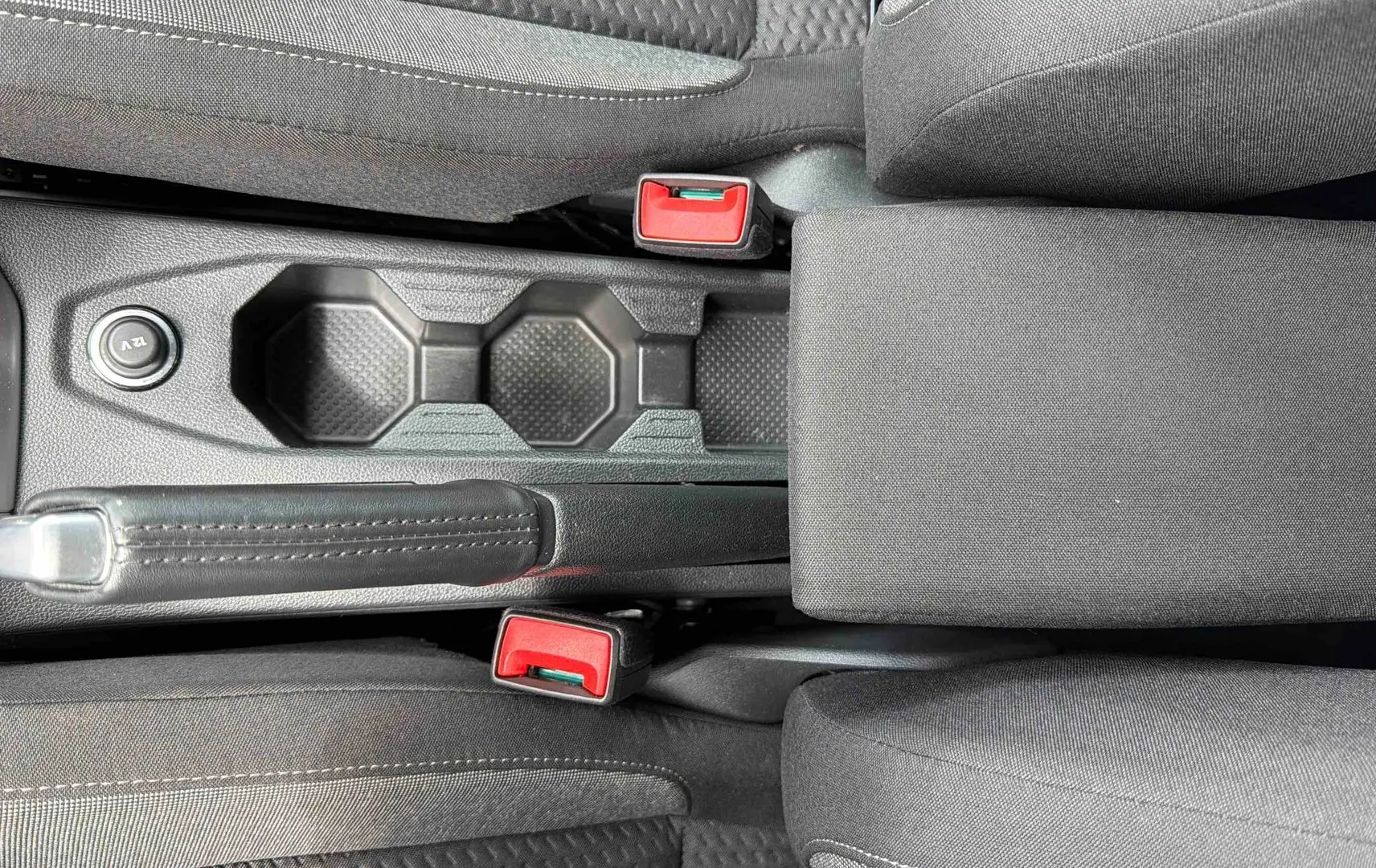 Vue plongeante sur la console centrale grise de la Volkswagen Polo 2025 avec frein à main et porte-gobelets.