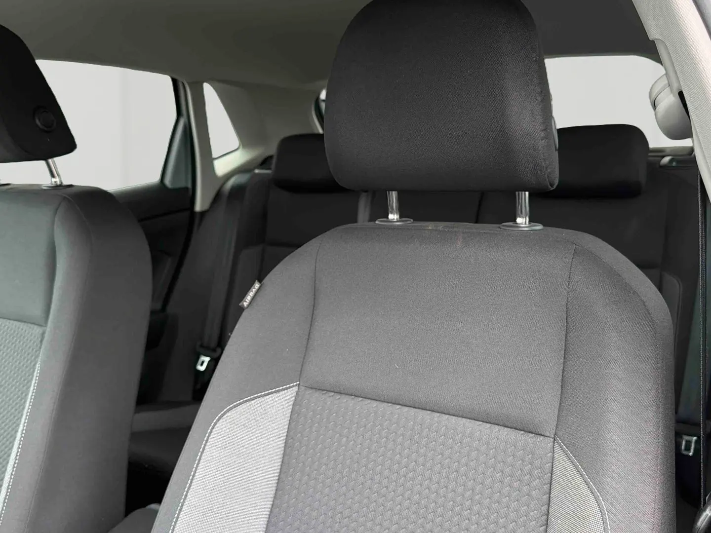 Gros plan sur le siège avant droit gris de la Volkswagen Polo 2025, tissu bi-ton avec appuie-tête intégré.