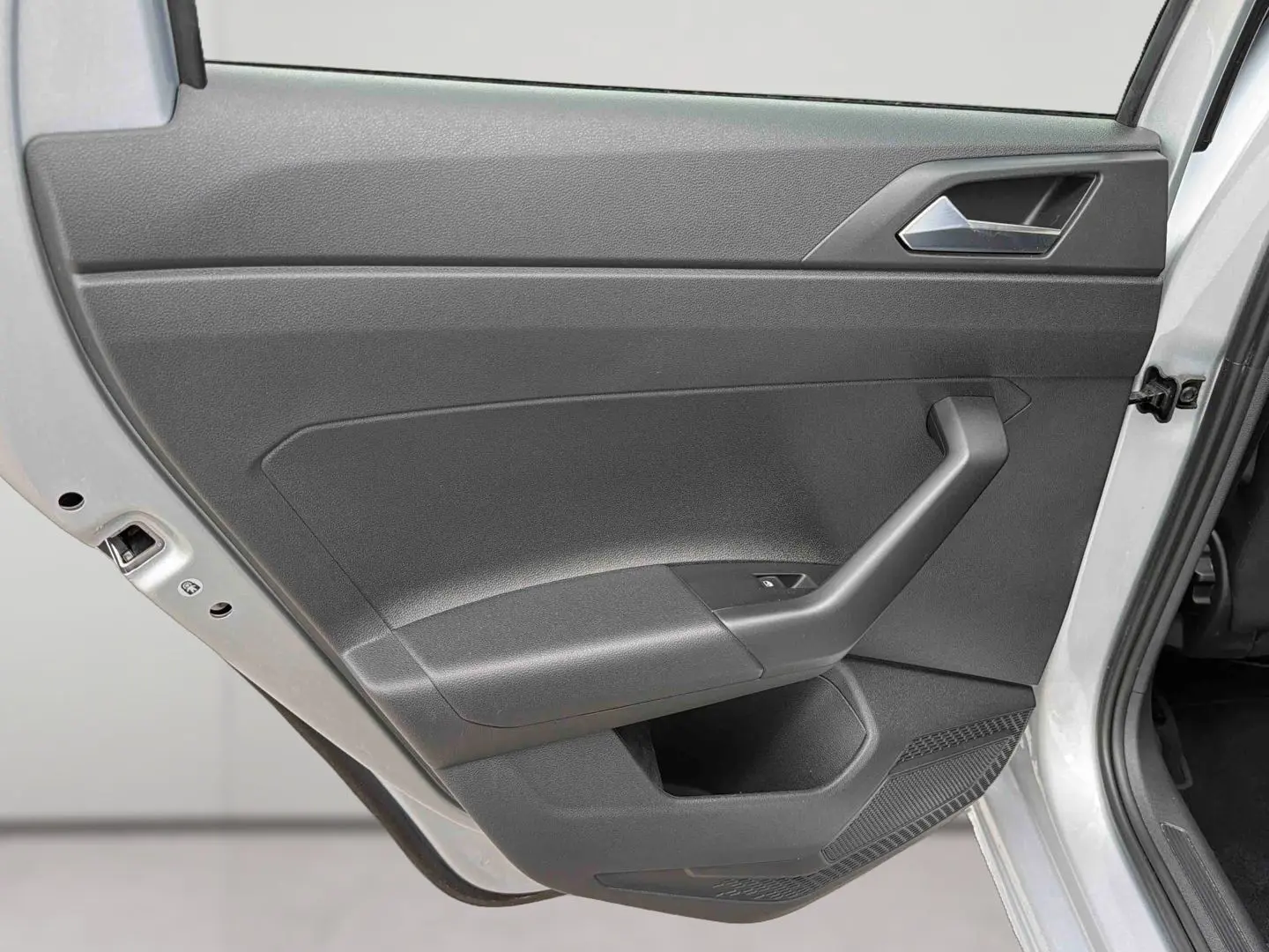 Vue rapprochée de la porte arrière droite grise d'une Volkswagen Polo 2025, avec poignée et commande de vitre visible.