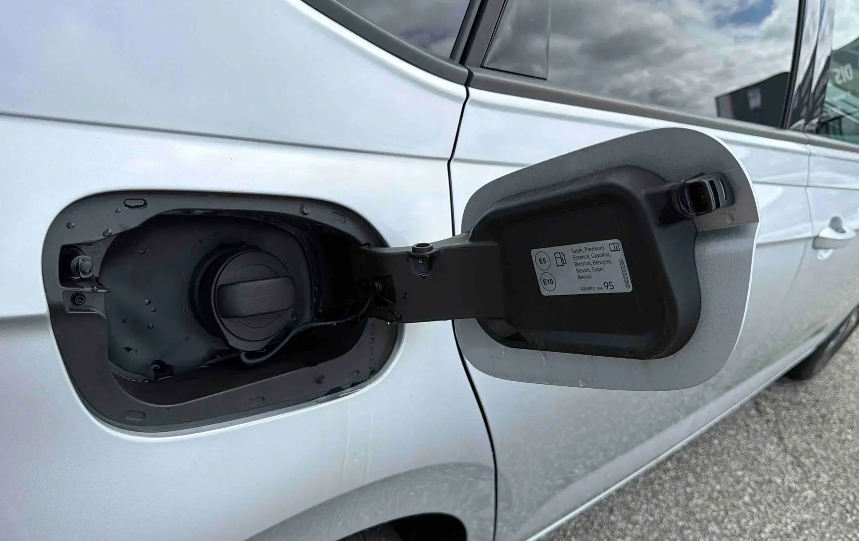 Vue rapprochée de la trappe à carburant ouverte côté gauche d’une Volkswagen Polo grise 2025.